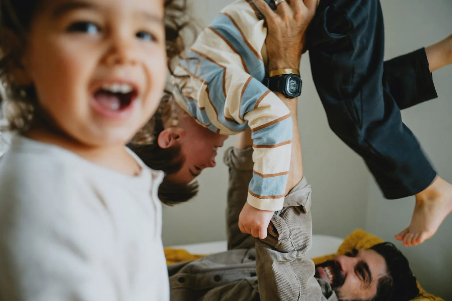 A father rough housing on his bed with his two little sons, somewhere near Asheville North Carolina during a family photo shoot with the world's best family photographer, Melina Coogan