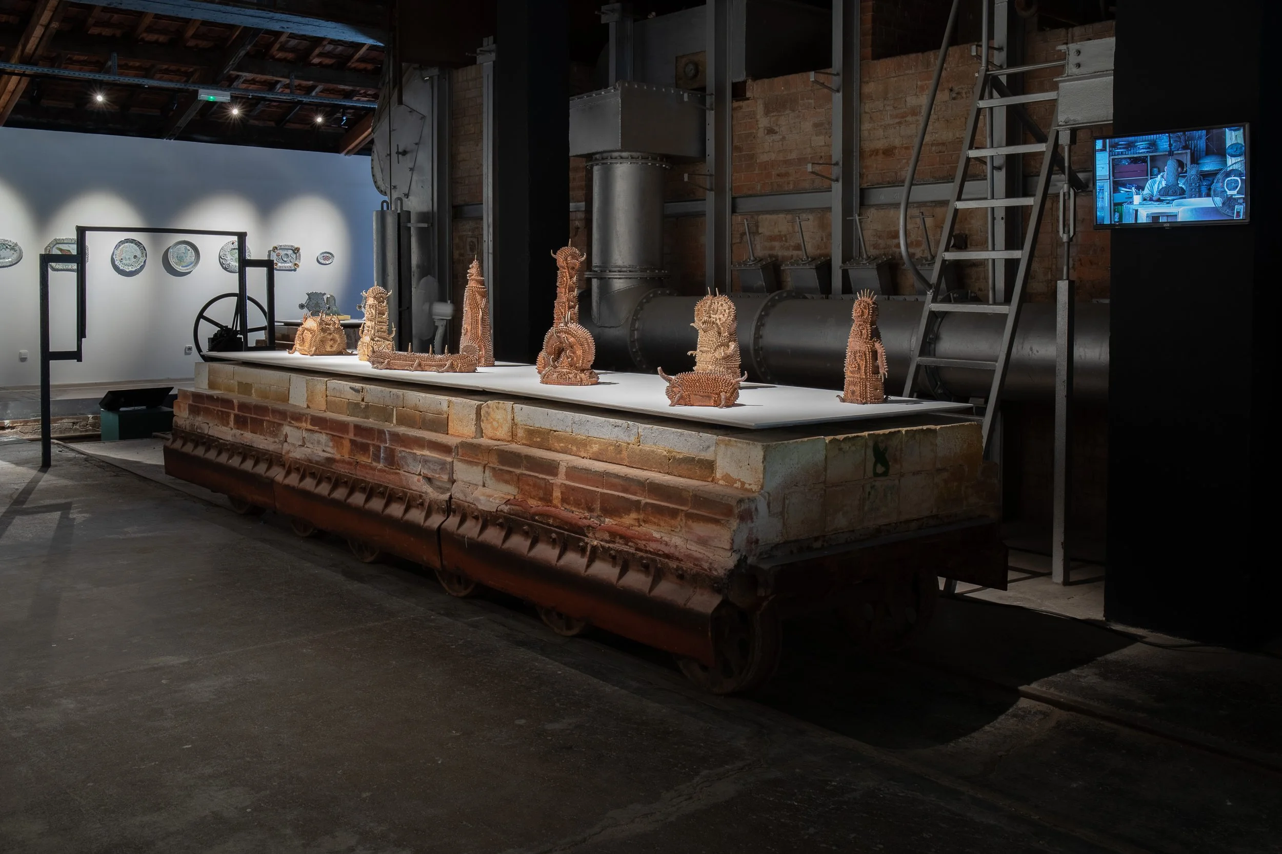 An installation photograph of Sawada's ceramics laid out across a white piece of wood hovering over a red brick base.