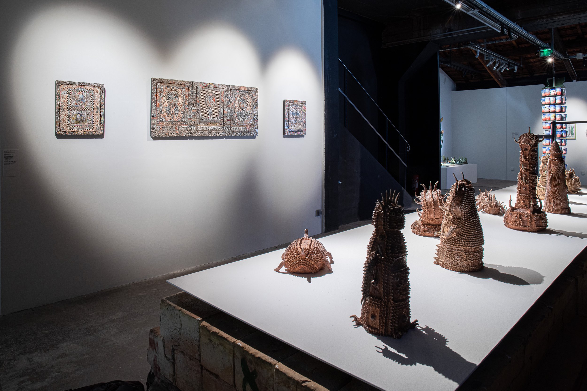 An installation photograph of Sawada's ceramics laid out across a white piece of wood hovering over a red brick base.