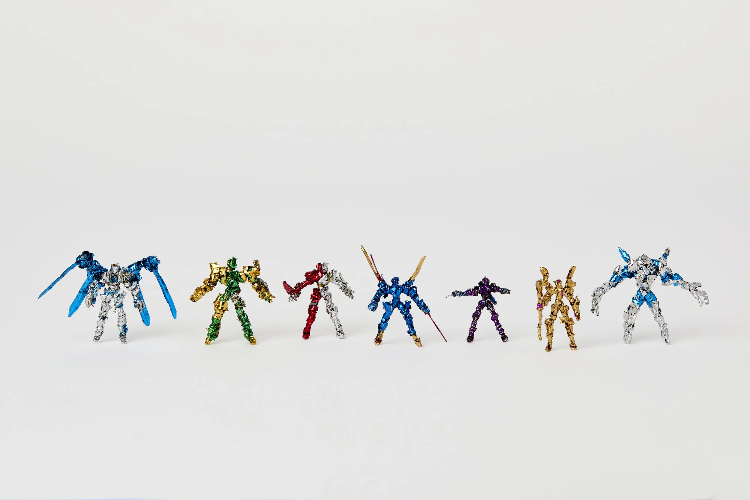 a series of 7 small warriors lined up all in different metallic colours, made from vinyl ties