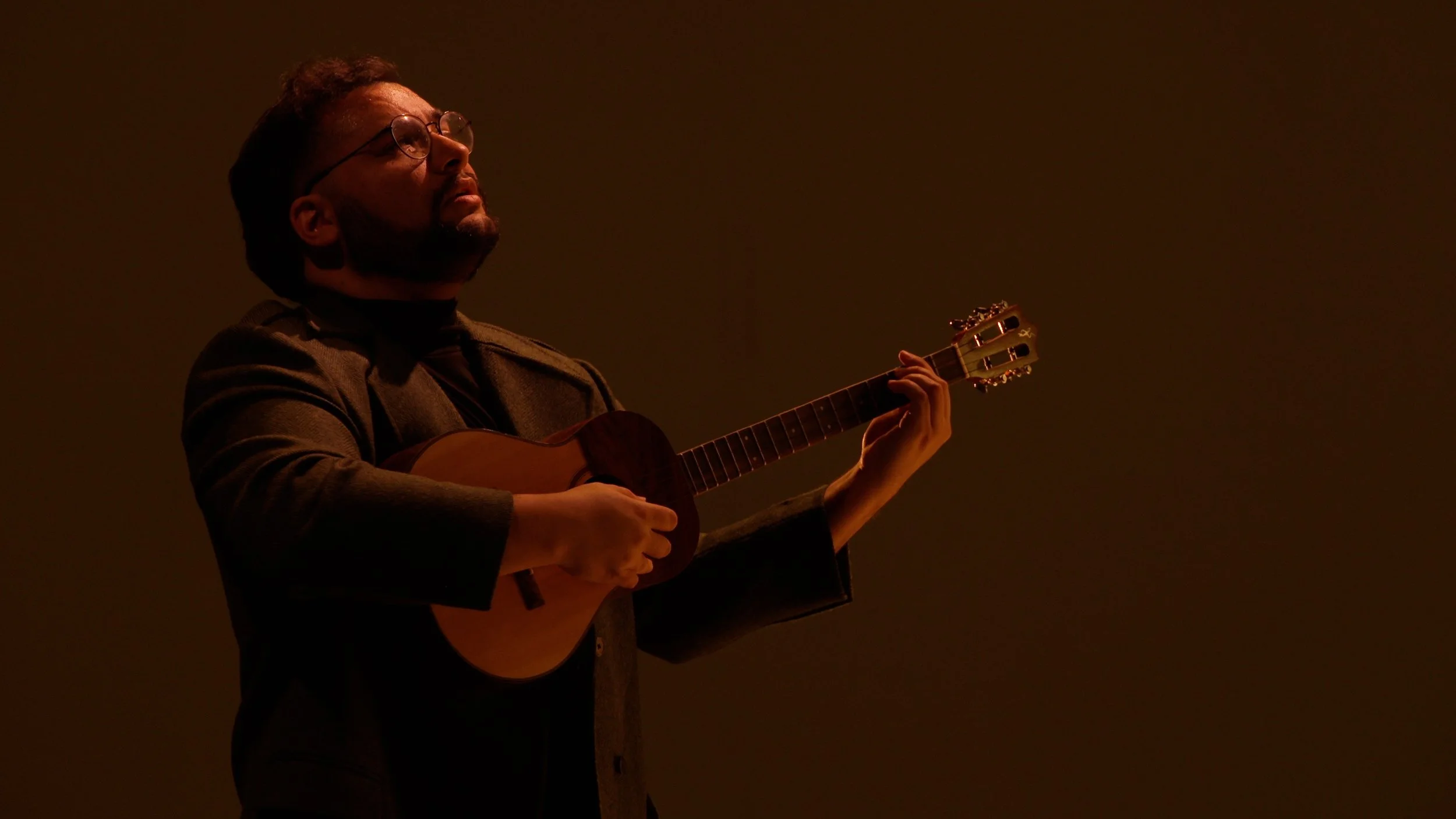 Man playing cuatro in dim lighting