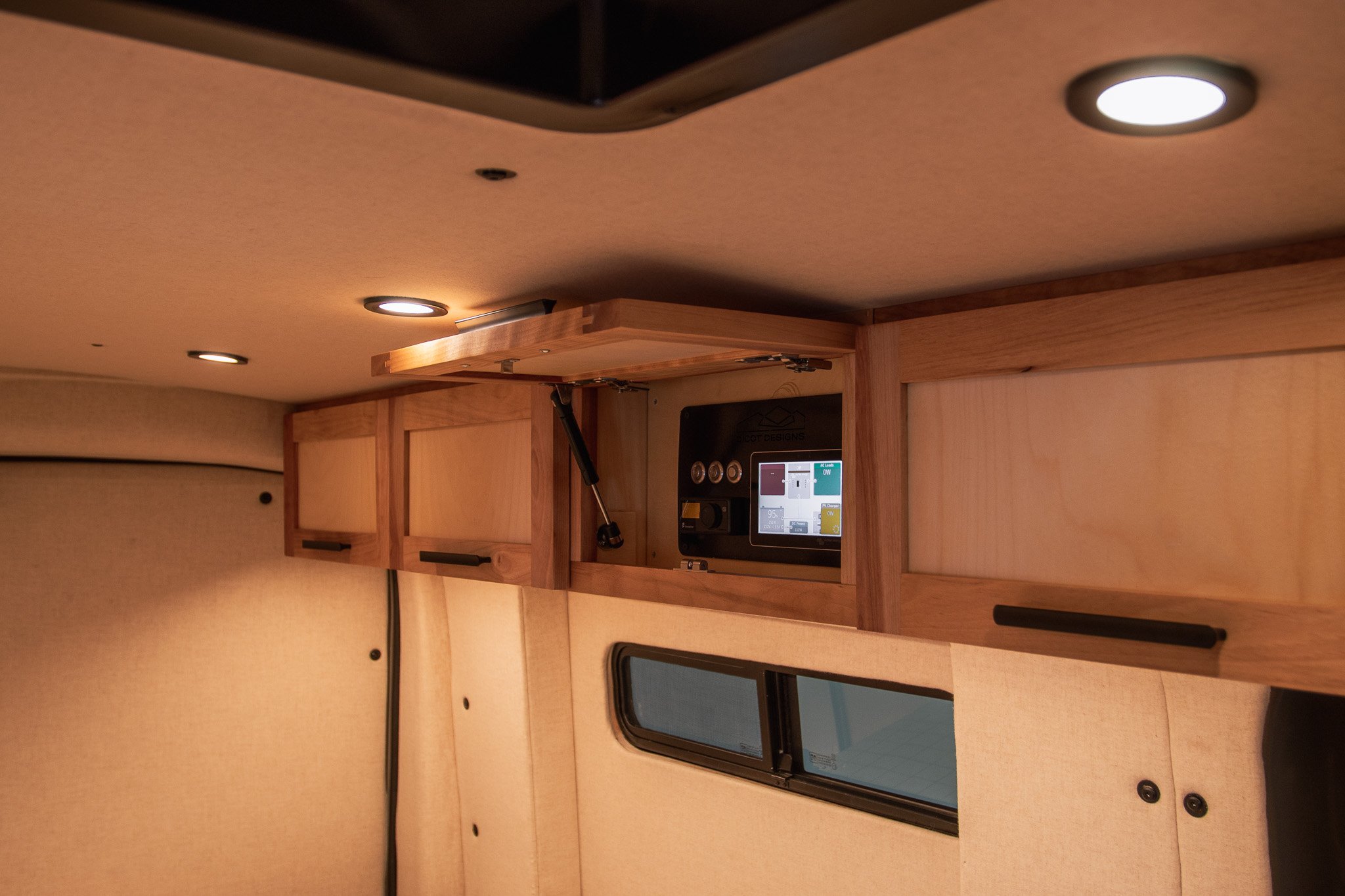 Interior of a camper van with wooden cabinets and LED lights