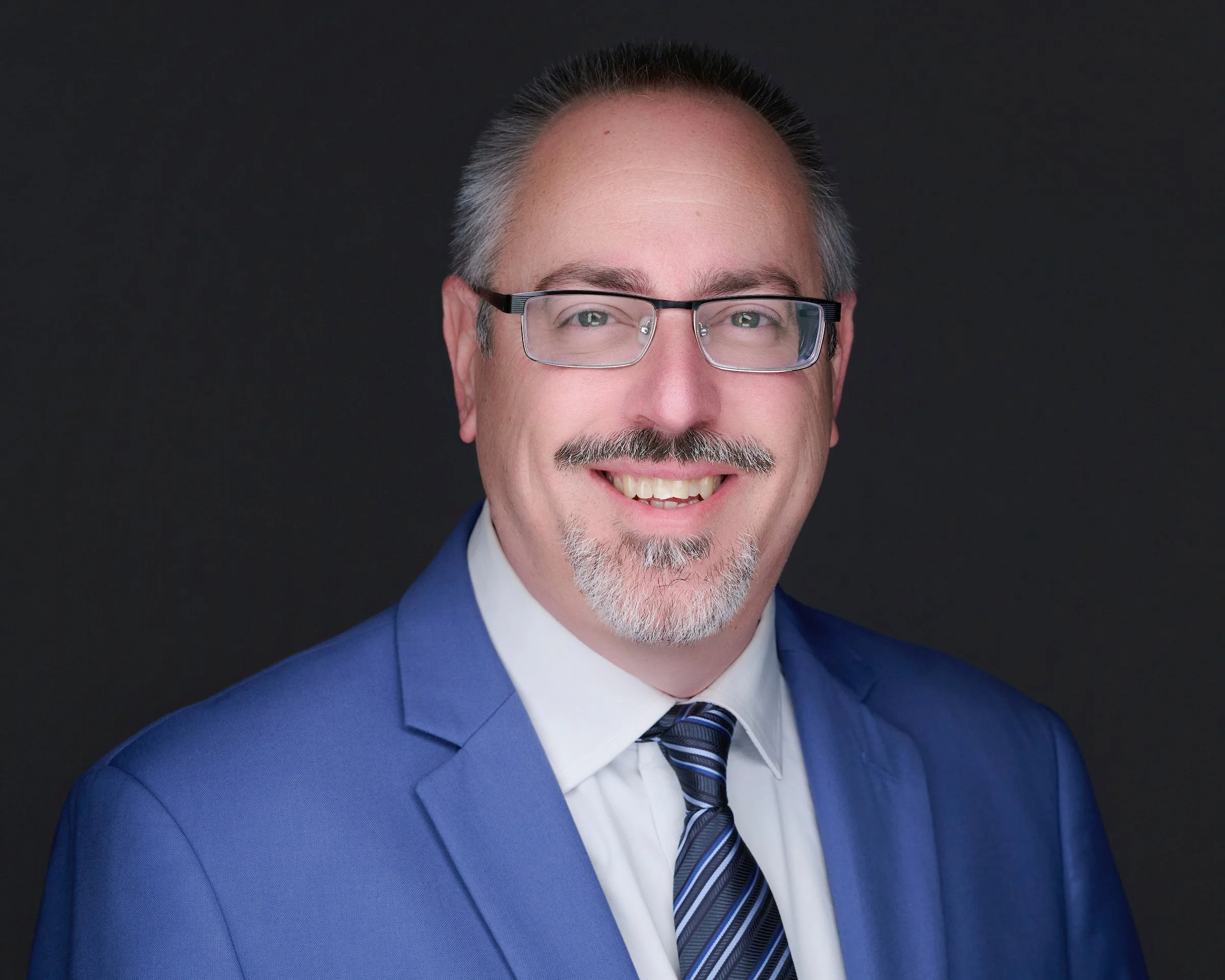 image of smiling man wearing suit with glasses and beard