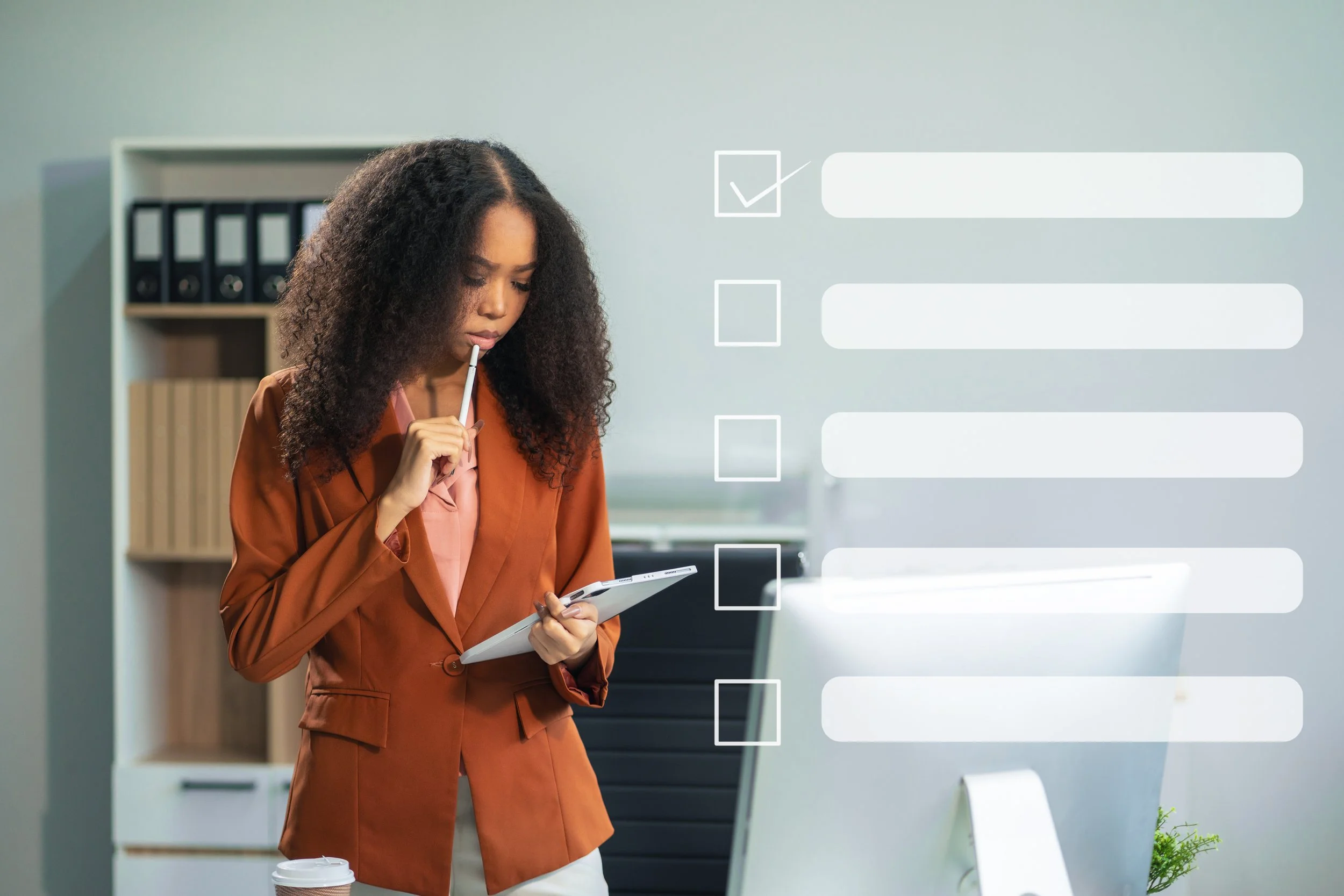 A woman in a brown blazer stands in an office, holding a notepad and pen, looking at the computer screen with a thinking expression. Overlaid are white digital checkboxes and lines of text, resembling a digital checklist.