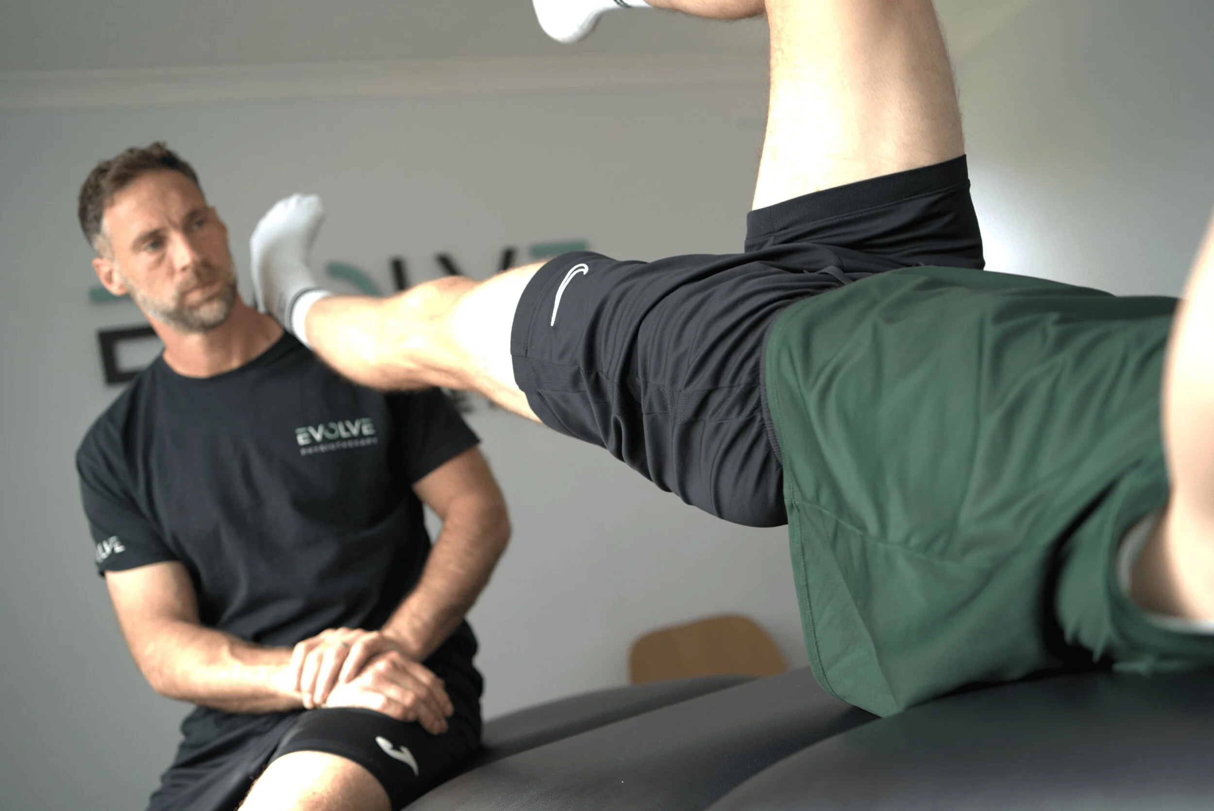Physiotherapist assessing an athlete's leg raise at Evolve Physiotherapy, Swansea