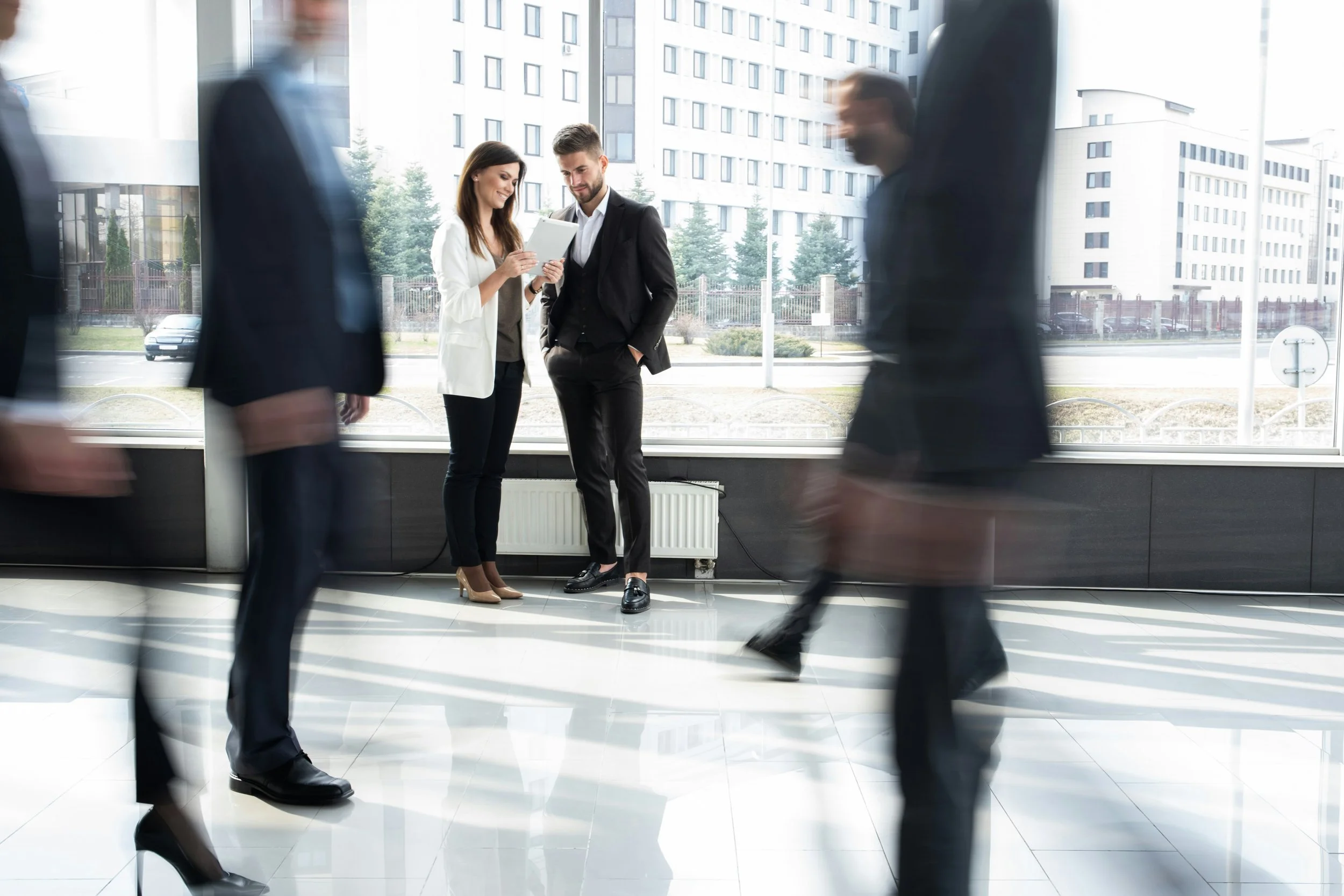 Professionals in motion through a law firm lobby while two colleagues pause to connect, the stillness a culture reset is meant to create.