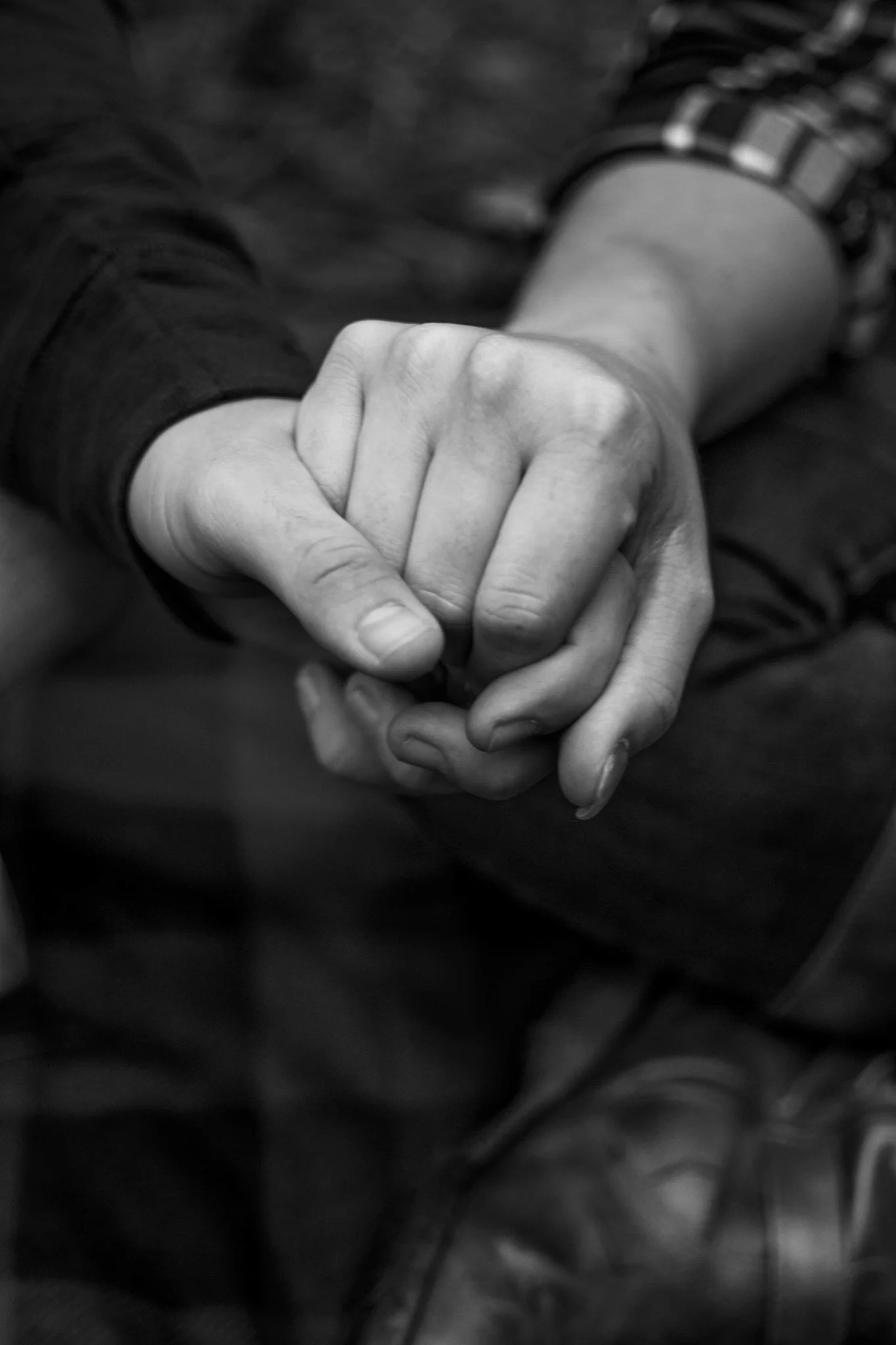 Black and white photo of two people holding hands, conveying a sense of connection and support.