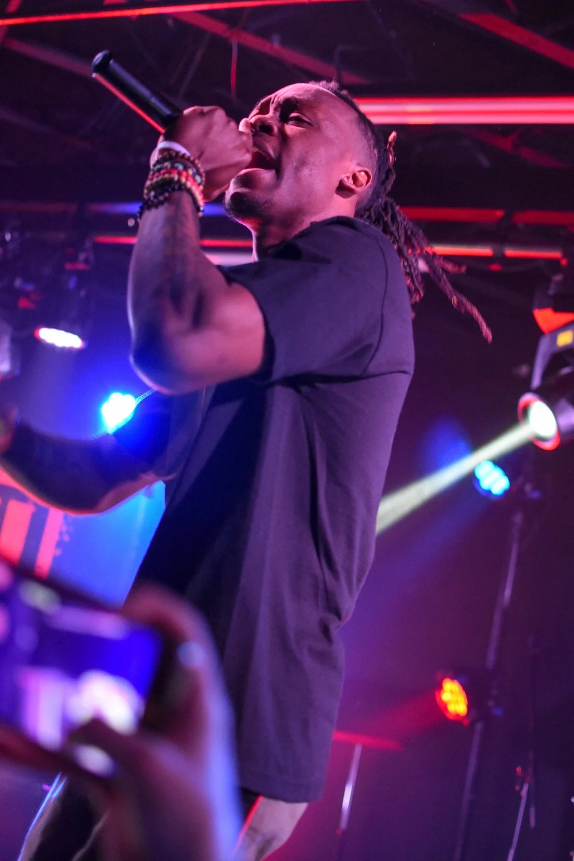 Performer with microphone on stage, colorful lights in background