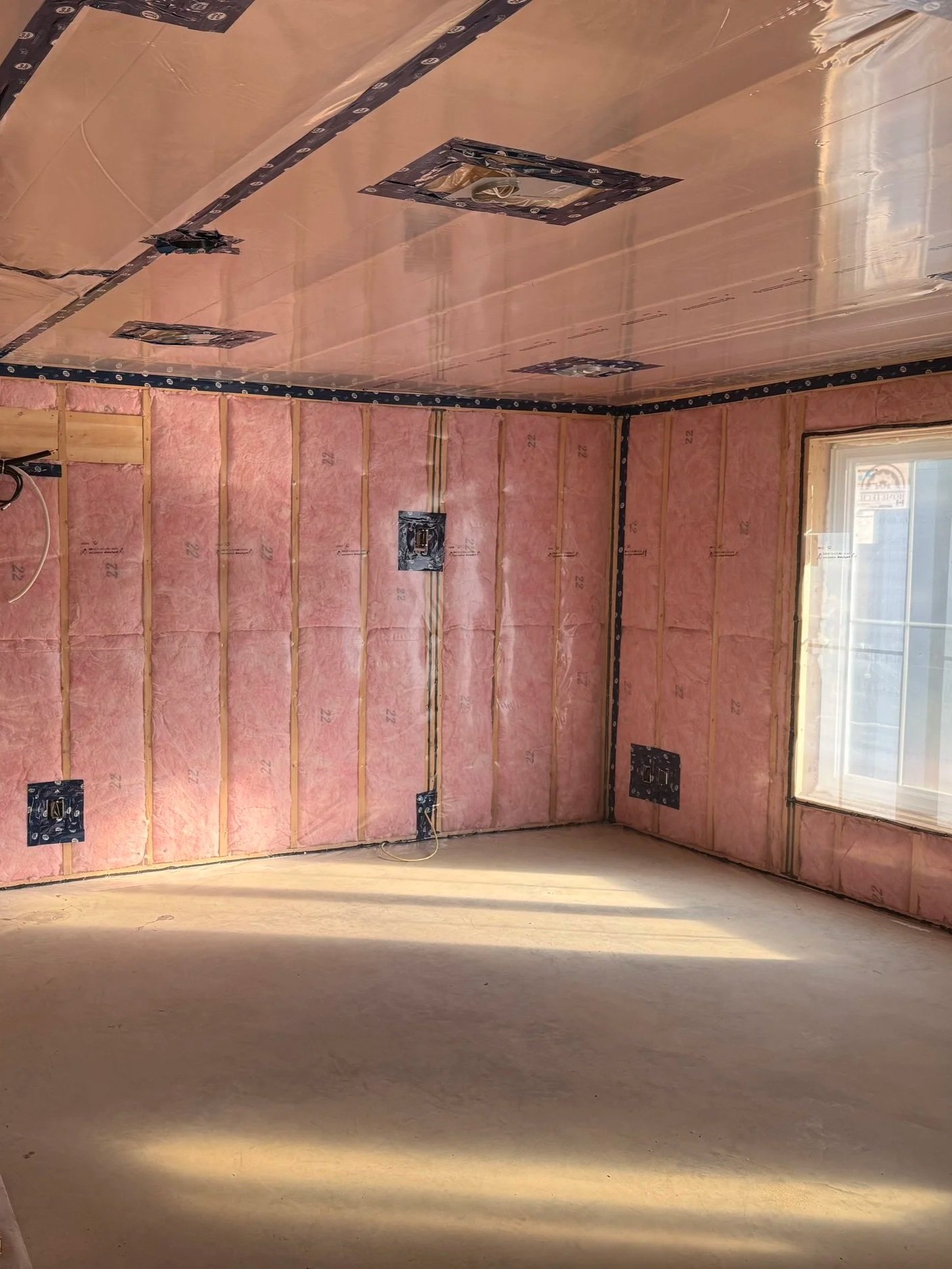 Room under construction with batt insulation on the walls, electrical boxes and wiring installed, and a window on the right side. ARU project in woodstock
