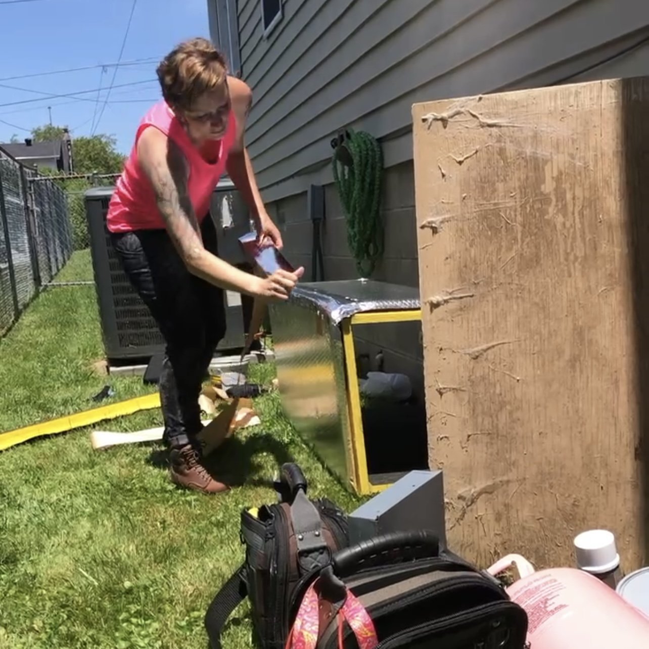 A woman applies foil tape to HVAC ductwork