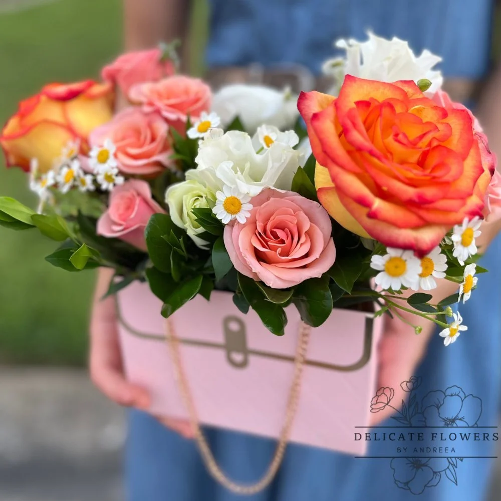 Urban Chic flower arrangement with orange and blush roses, white blooms, daisy accents, greenery, in a designer purse container — handcrafted same-day by Delicate Flowers by Andreea