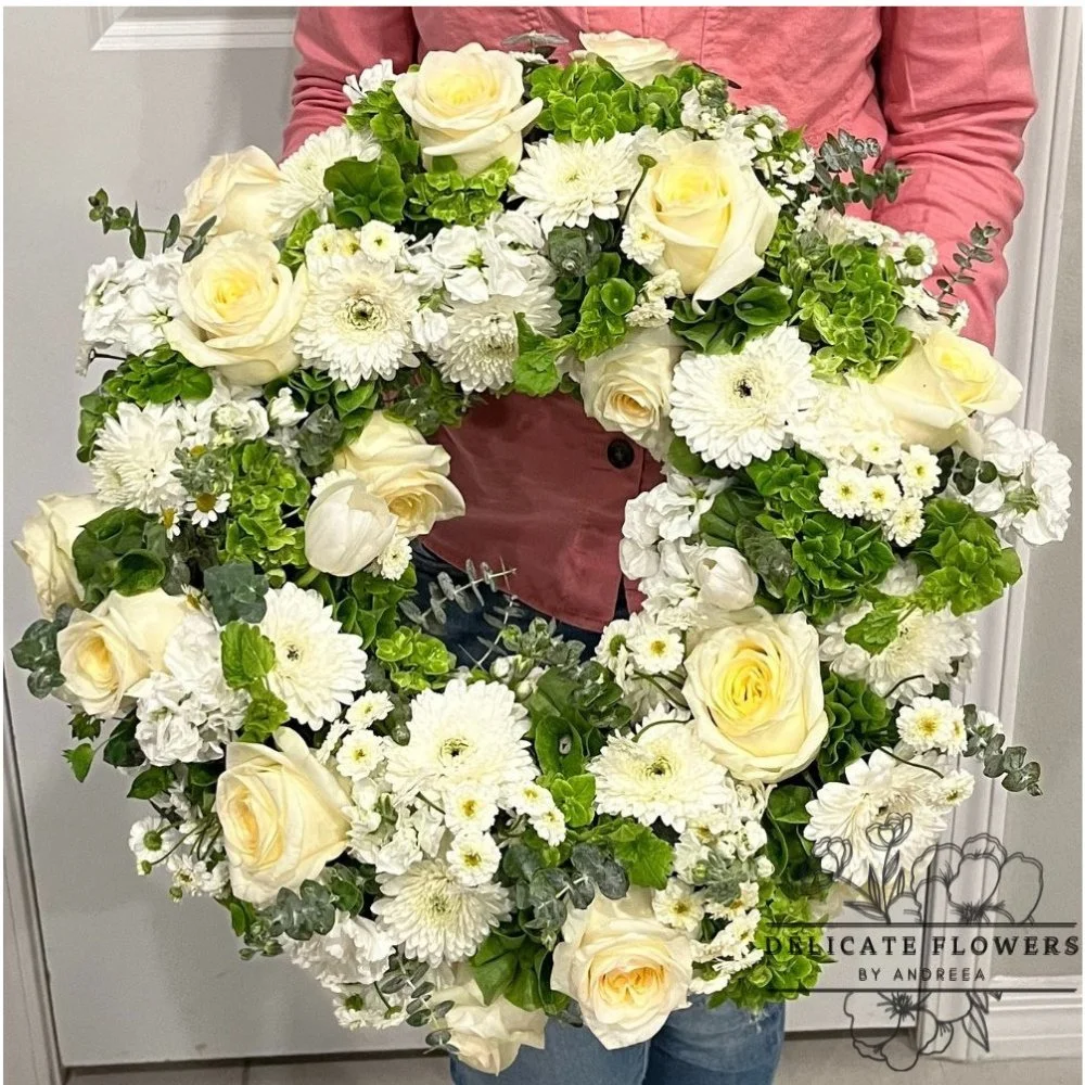 Ivory white sympathy wreath with roses, mums, green hydrangea, eucalyptus, and seasonal white blooms