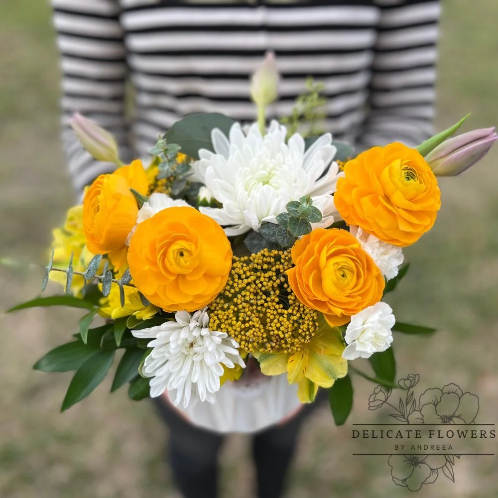 Yellow Haven flower arrangement with yellow ranunculus, iris, and eucalyptus