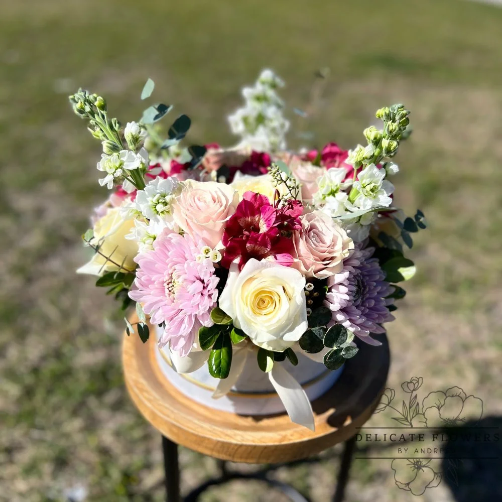 Soft pastel arrangement with ivory and blush roses, lavender mums, alstroemeria, and delicate white blooms