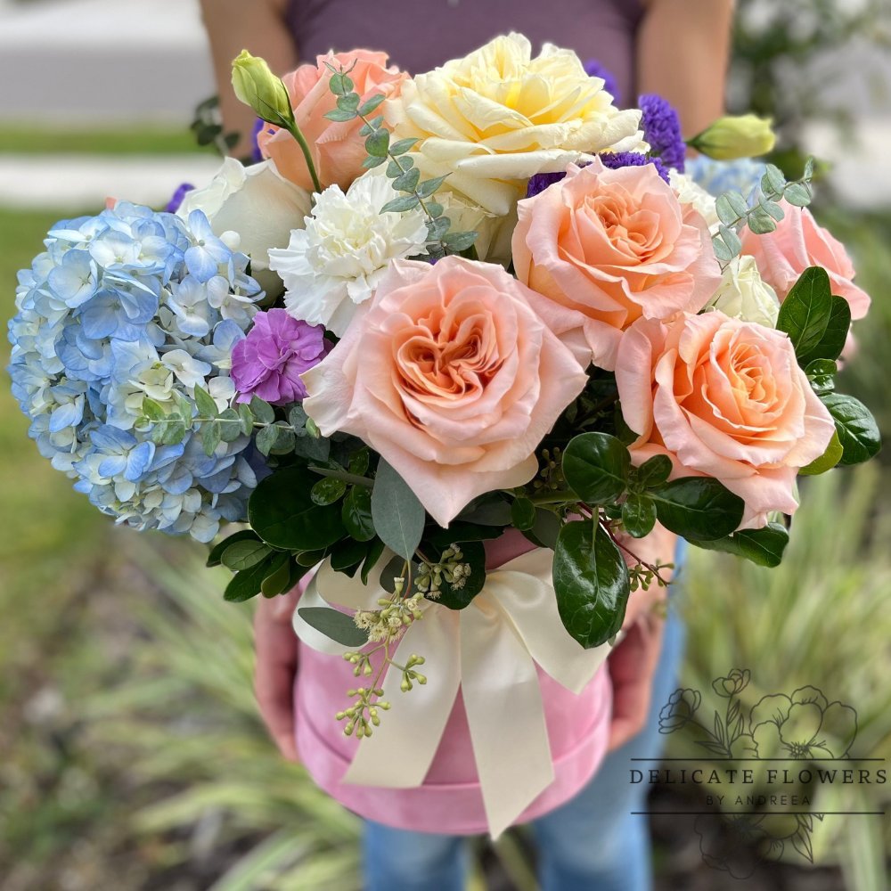 Mirage Symphony flower arrangement with peach roses, ivory blooms, blue hydrangea, lavender accents, and greenery