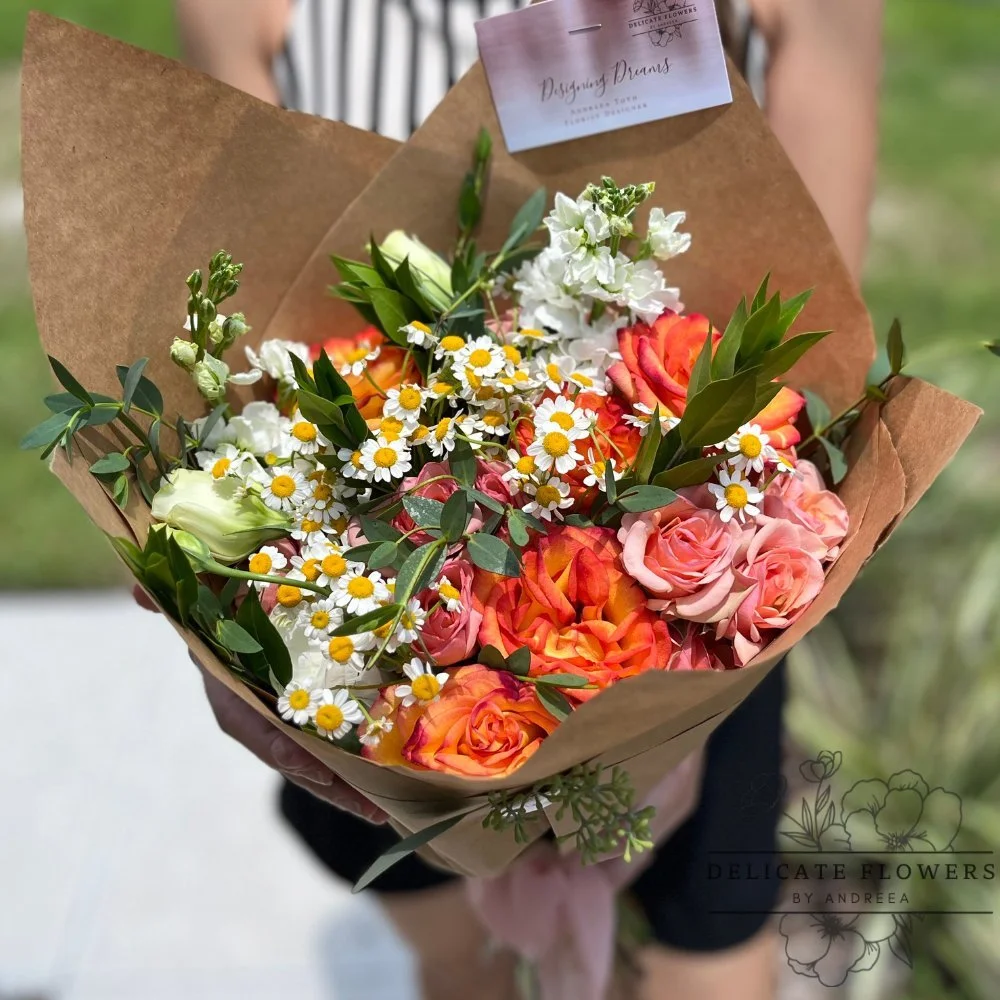 Back to School bouquet with orange and blush roses, white daisies, white blooms, greenery, wrapped in kraft paper