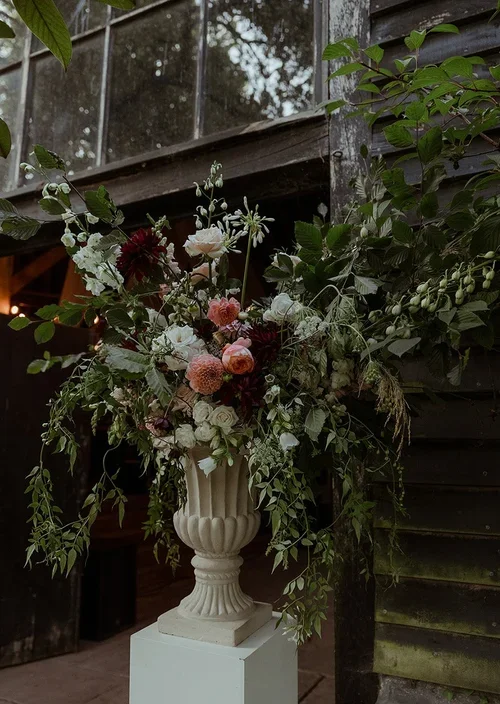 Updown-farmhouse-wedding-flowers-plinth-urn-outdoor.webp