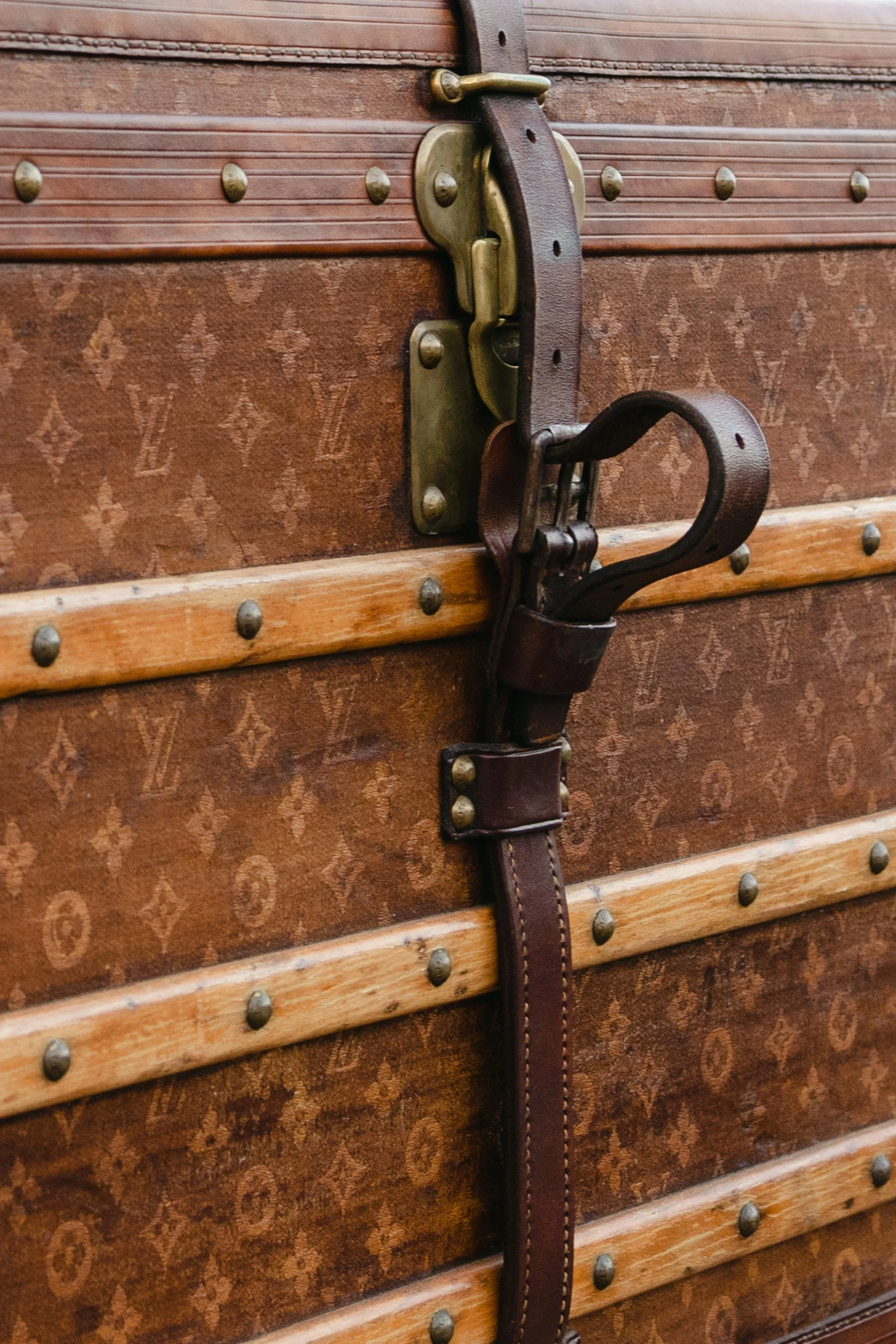 Close-up of a vintage wooden trunk with metal accents and a leather strap latch.