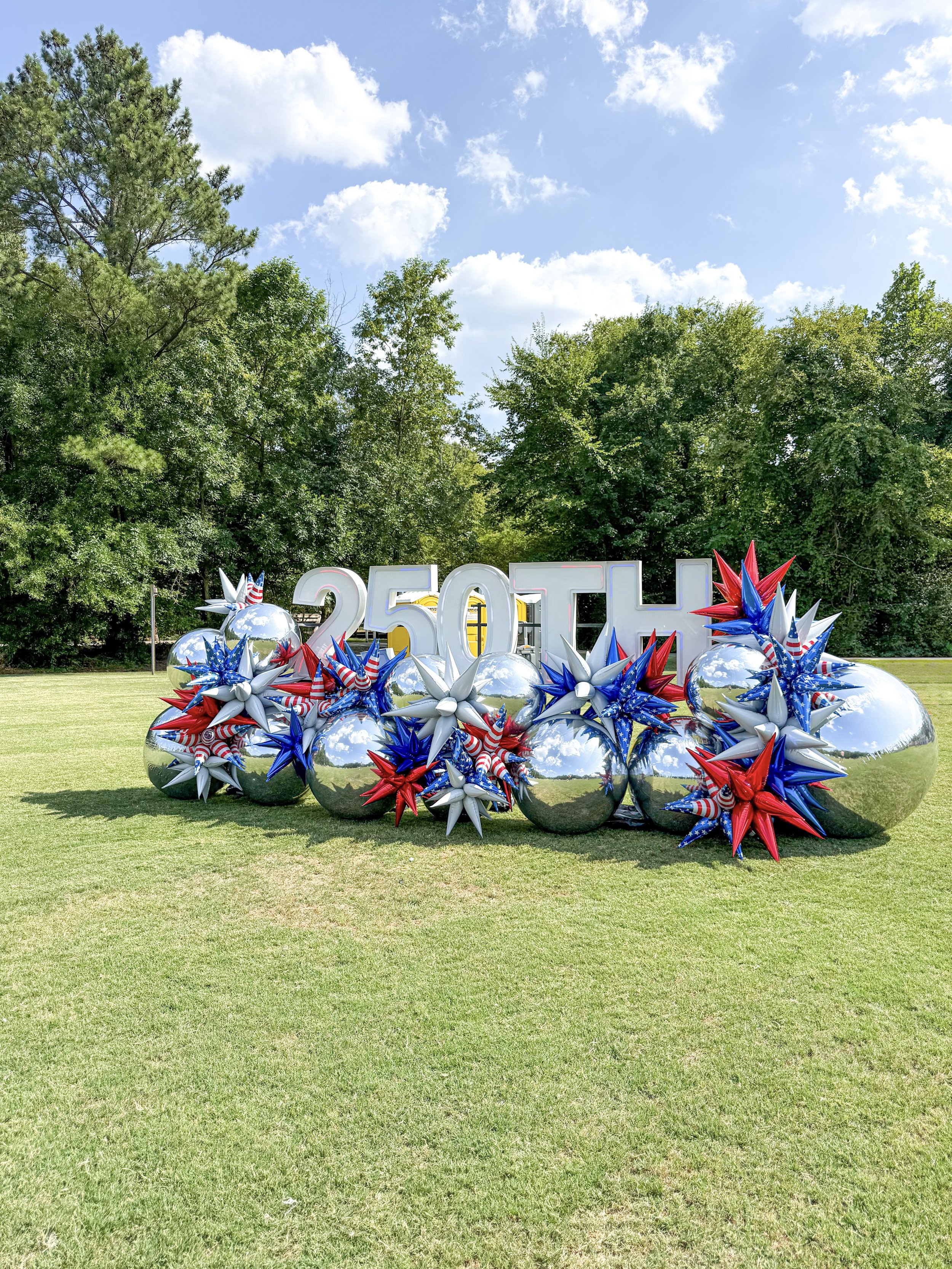 big shinny silver orbs with patriotic starburst balloons led marquees spelling 250th 
