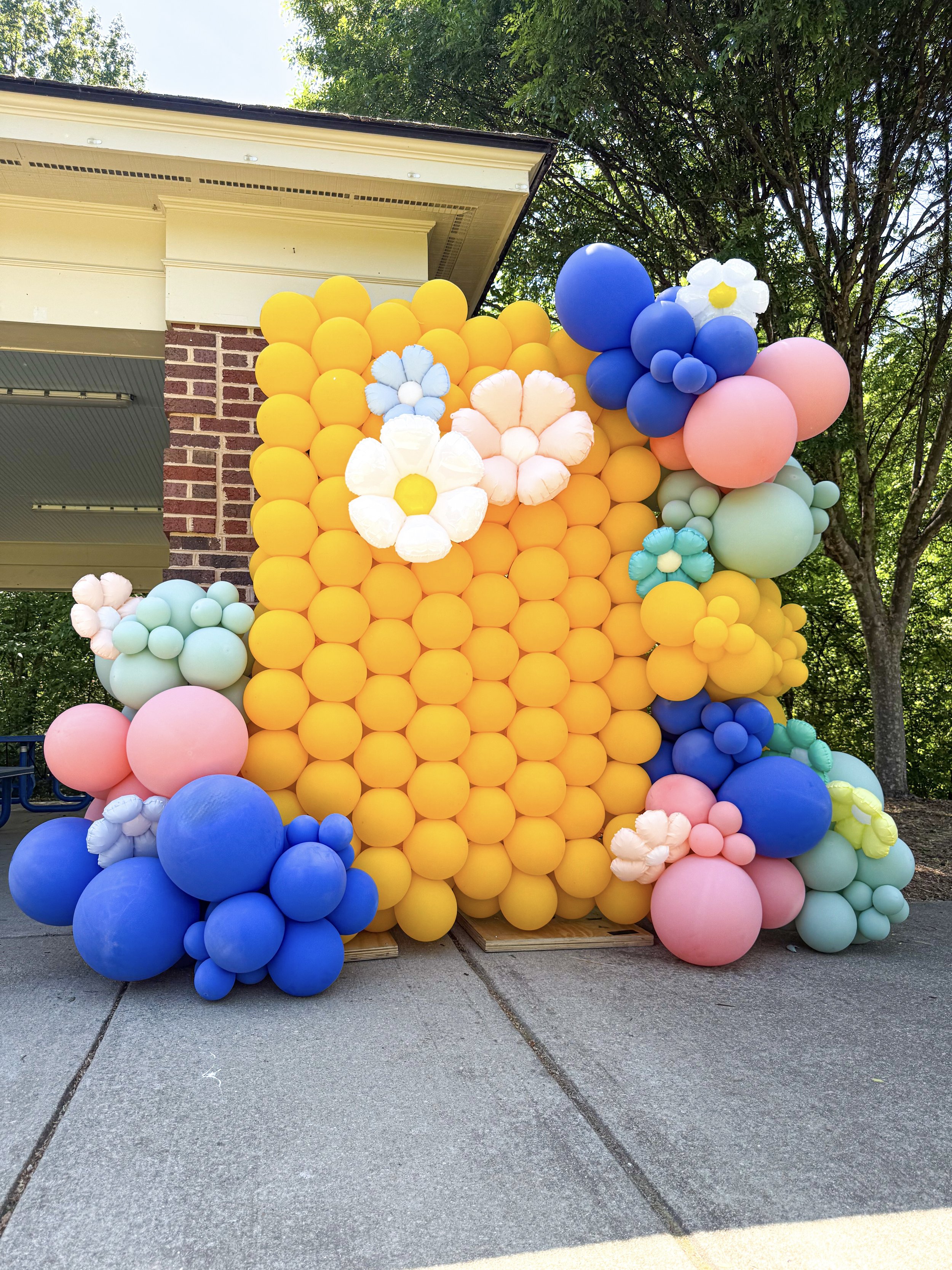 yellow balloon wall with blue, pink, mint organic garland balloons and daisy balloons