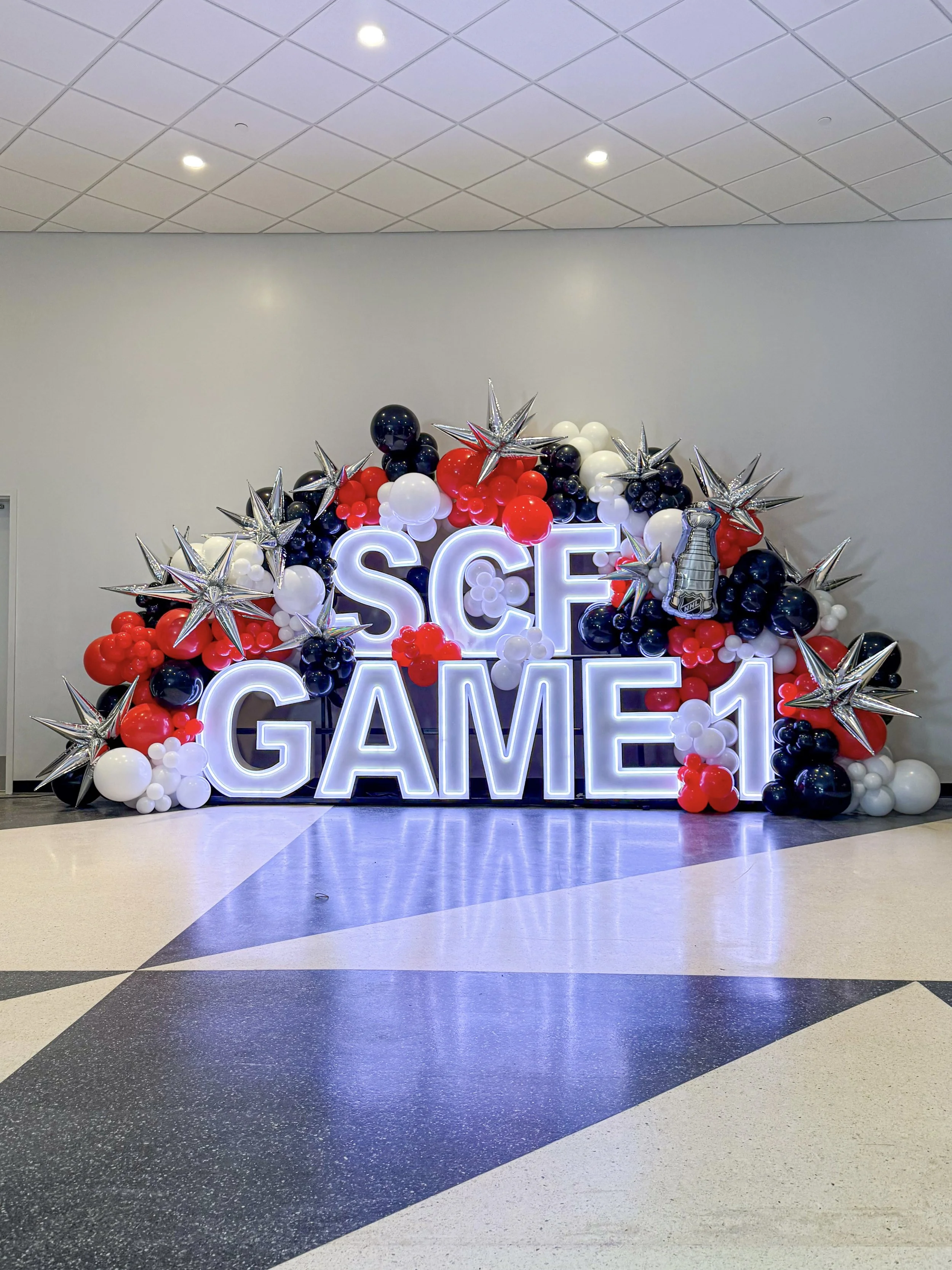 LED marquee letters spelling out SCF GAME 1 with red, black, white balloons with silver starburst for the Stanley cup