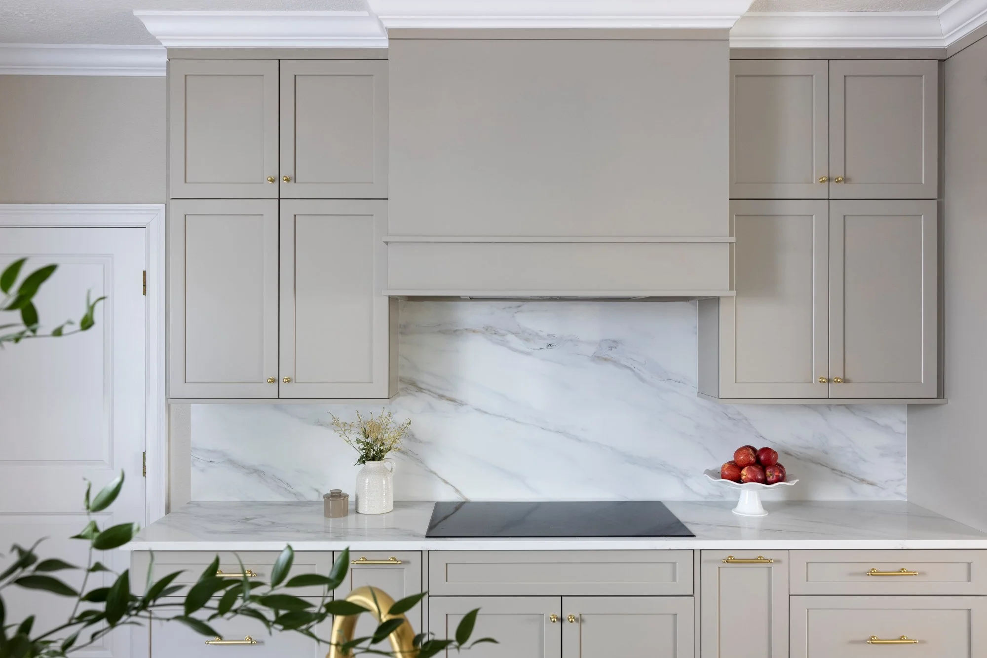 Close-up of a marble slab backsplash and range wall in a Palma Ceia kitchen renovation featuring dramatic stone veining and warm taupe cabinetry.
