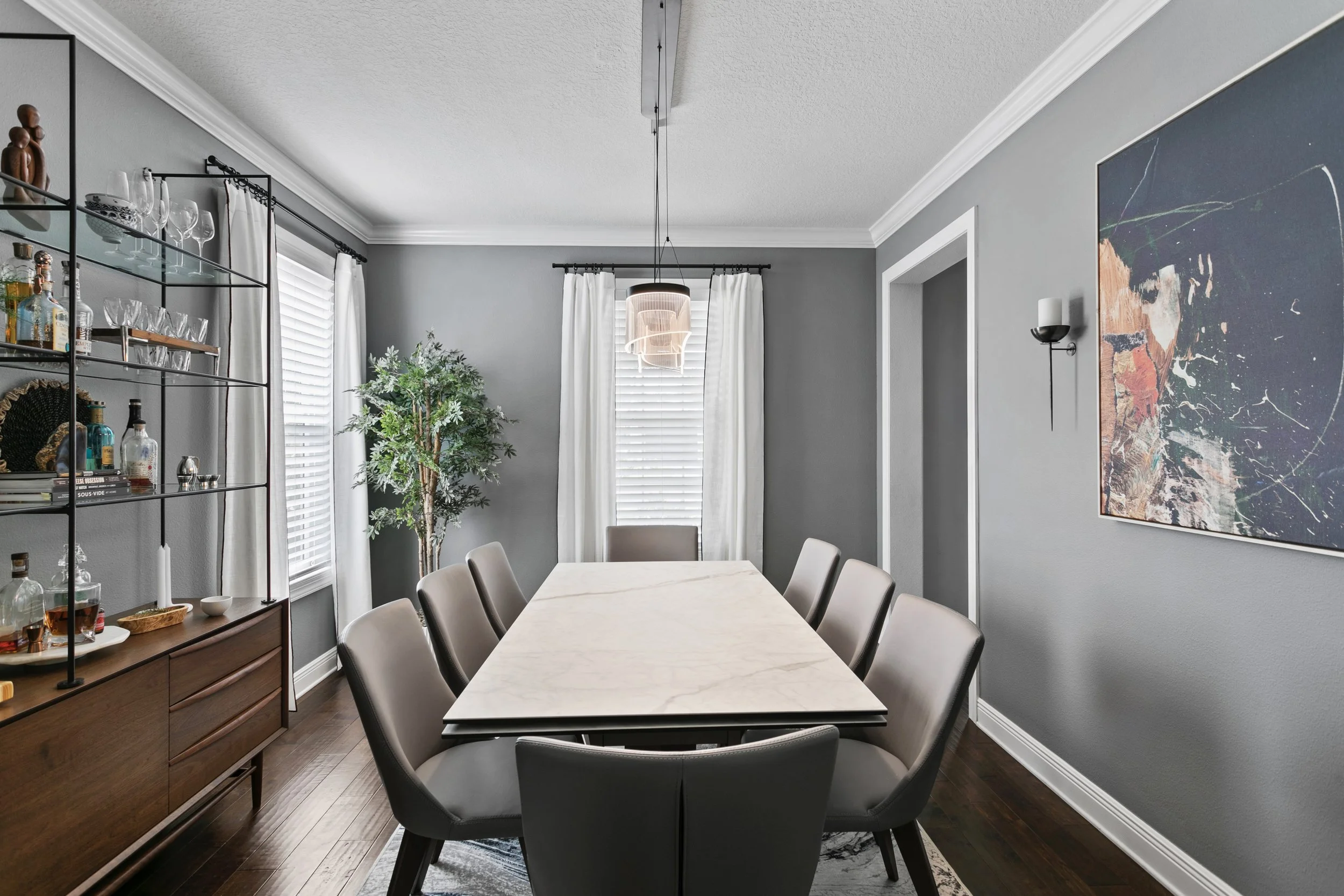 Dining room with gray walls, custom shelving and storage, and long dining table.