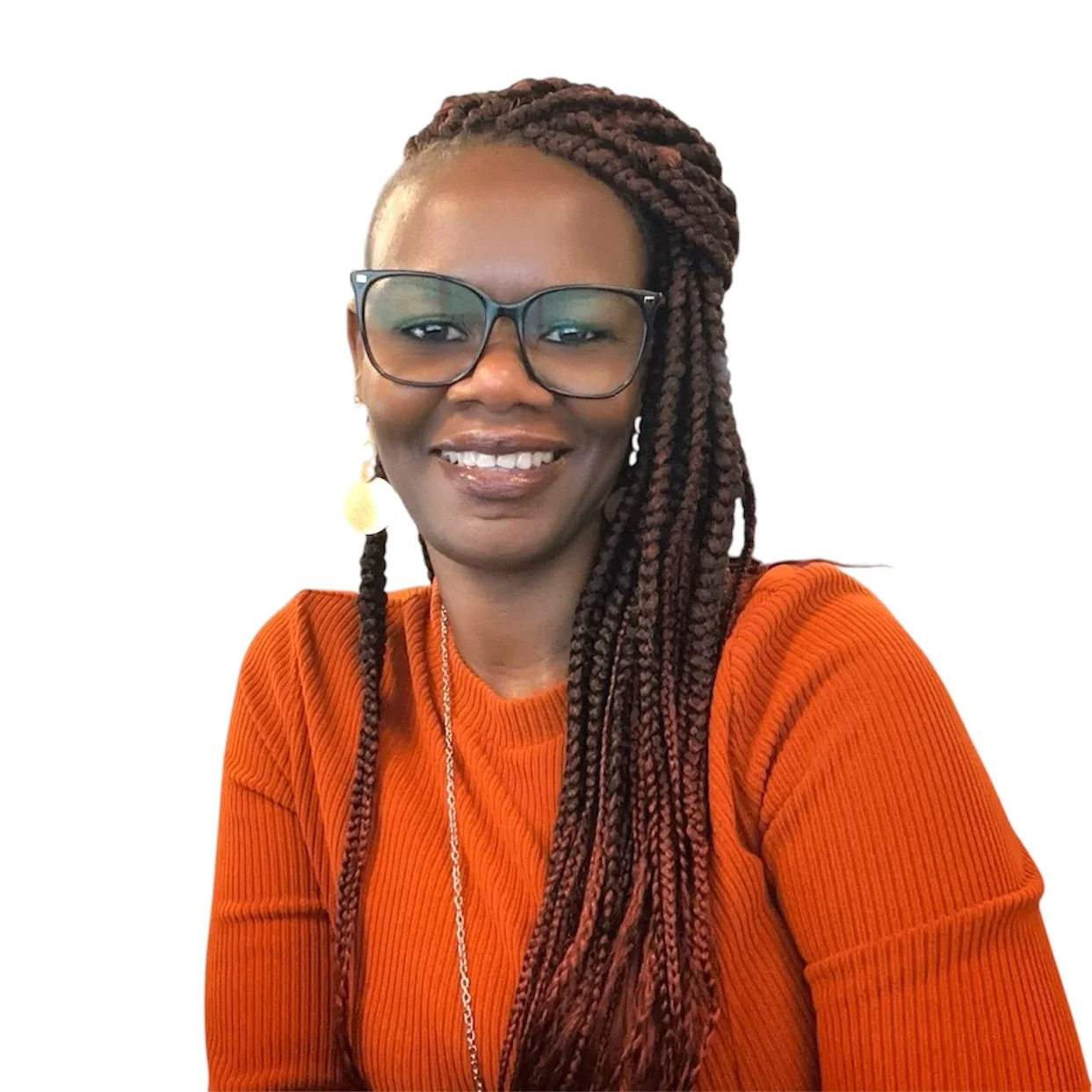 A smiling Black woman with long braided hair wearing glasses, gold earrings, and an orange sweater.