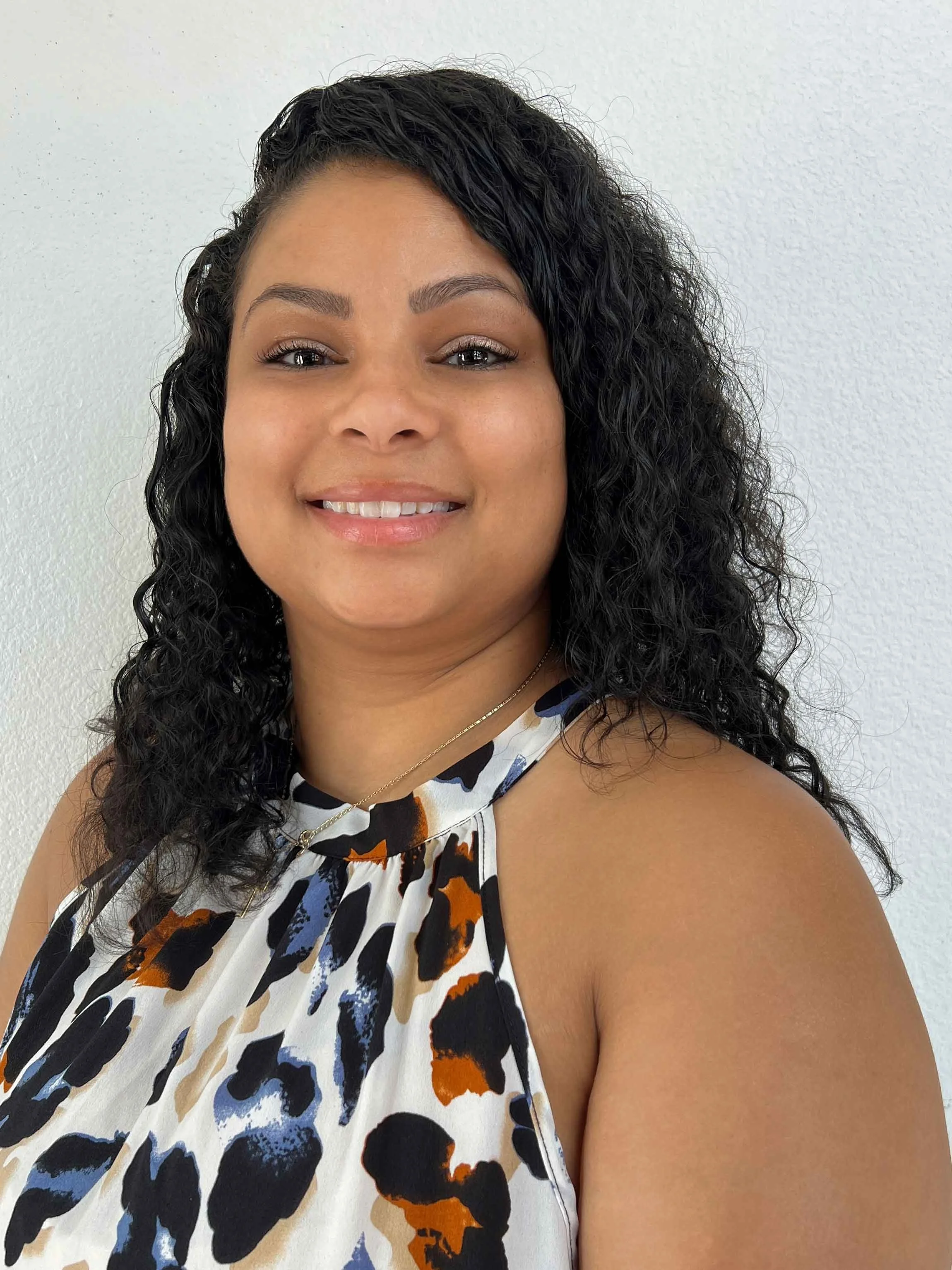 headshot picture of a female in a black top  and colorful earrings