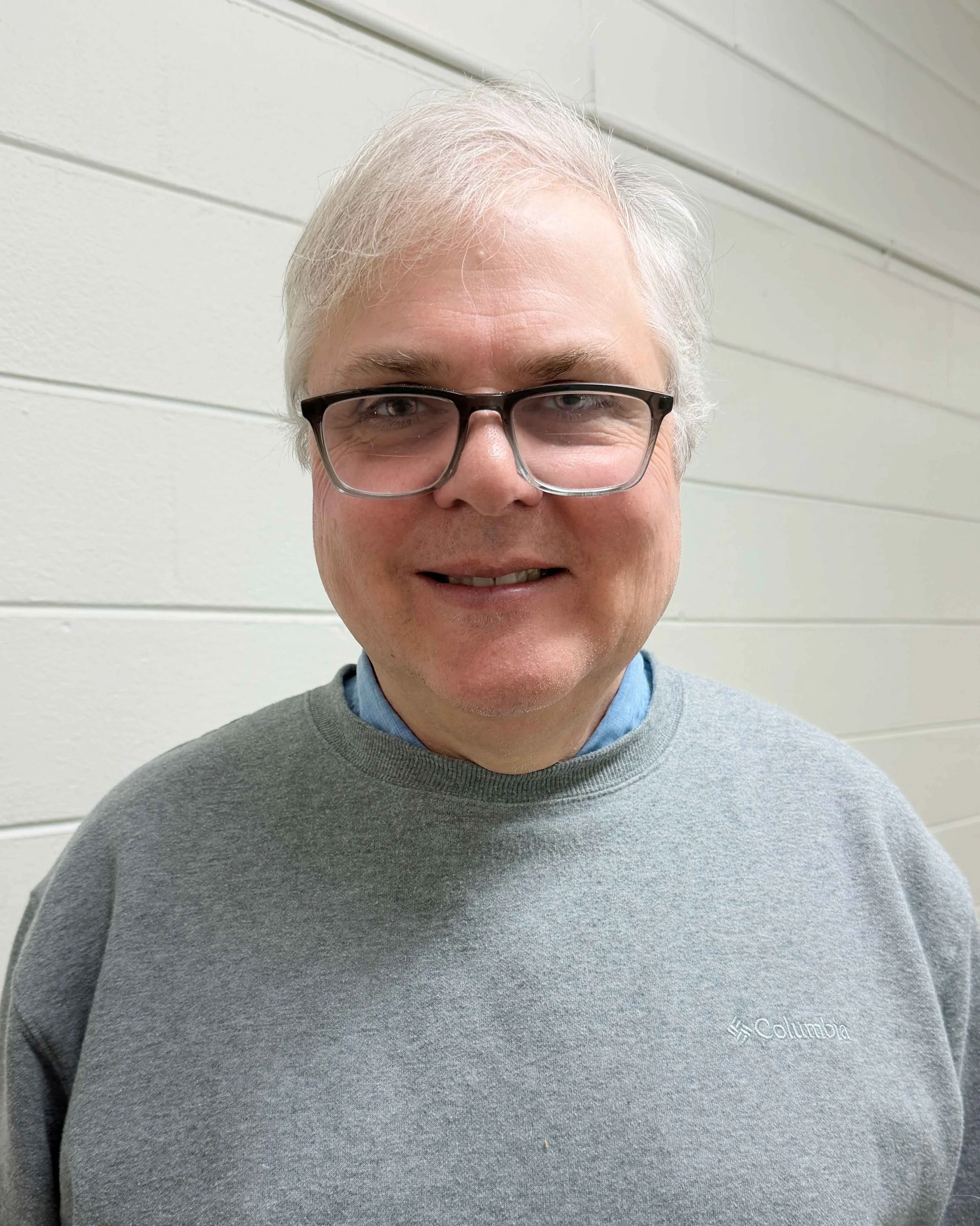 music teacher wearing a grey sweater and glasses