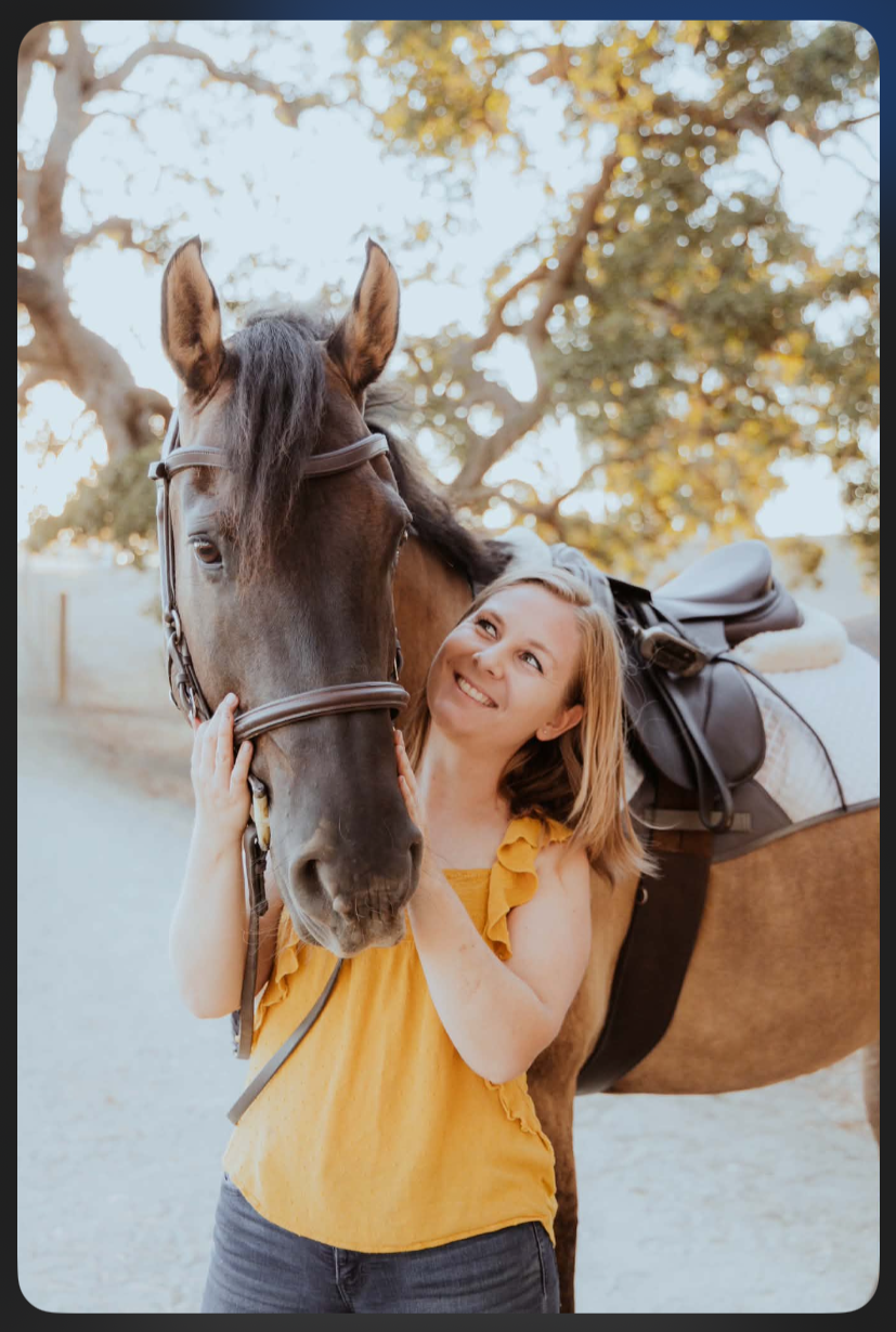 a brown horse weaering bridel and saddle and woman in yellow short smiling and holding her horse head between her hands both looking at each other in love