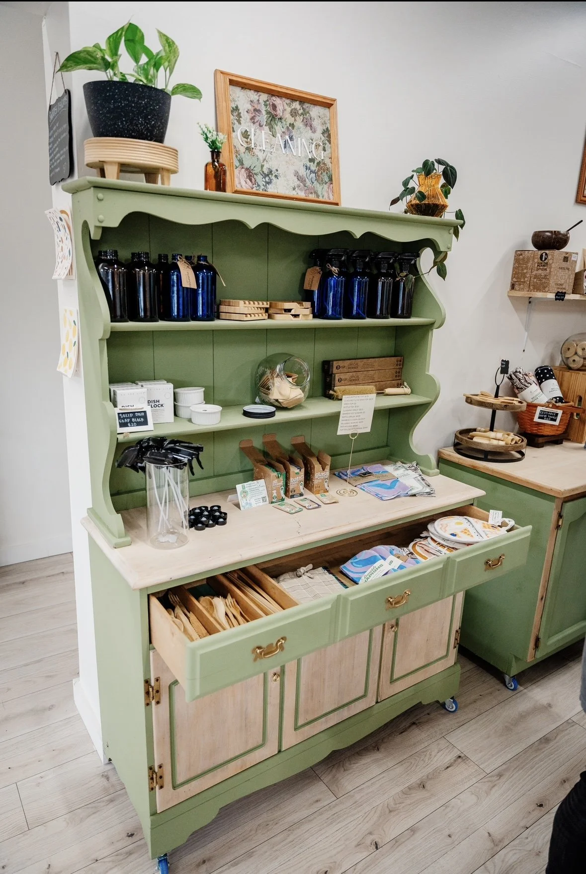 A light green wooden shelving unit displaying various kitchen and home decor items.