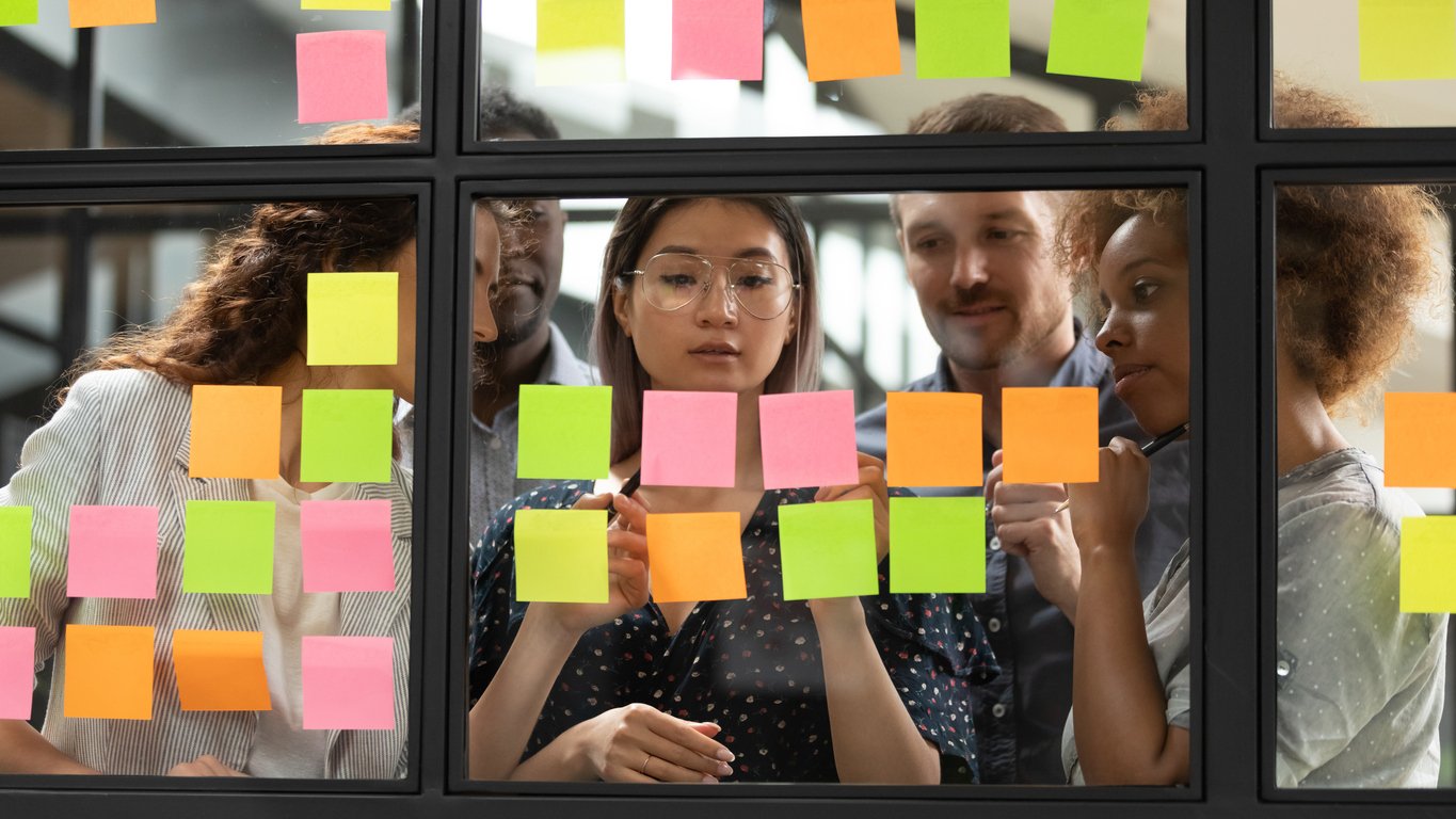 Scrum Team working together around post-it notes on a board