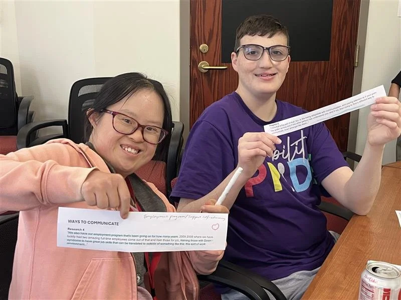 2 researchers with IDD review strips of paper with responses from questionnaires.