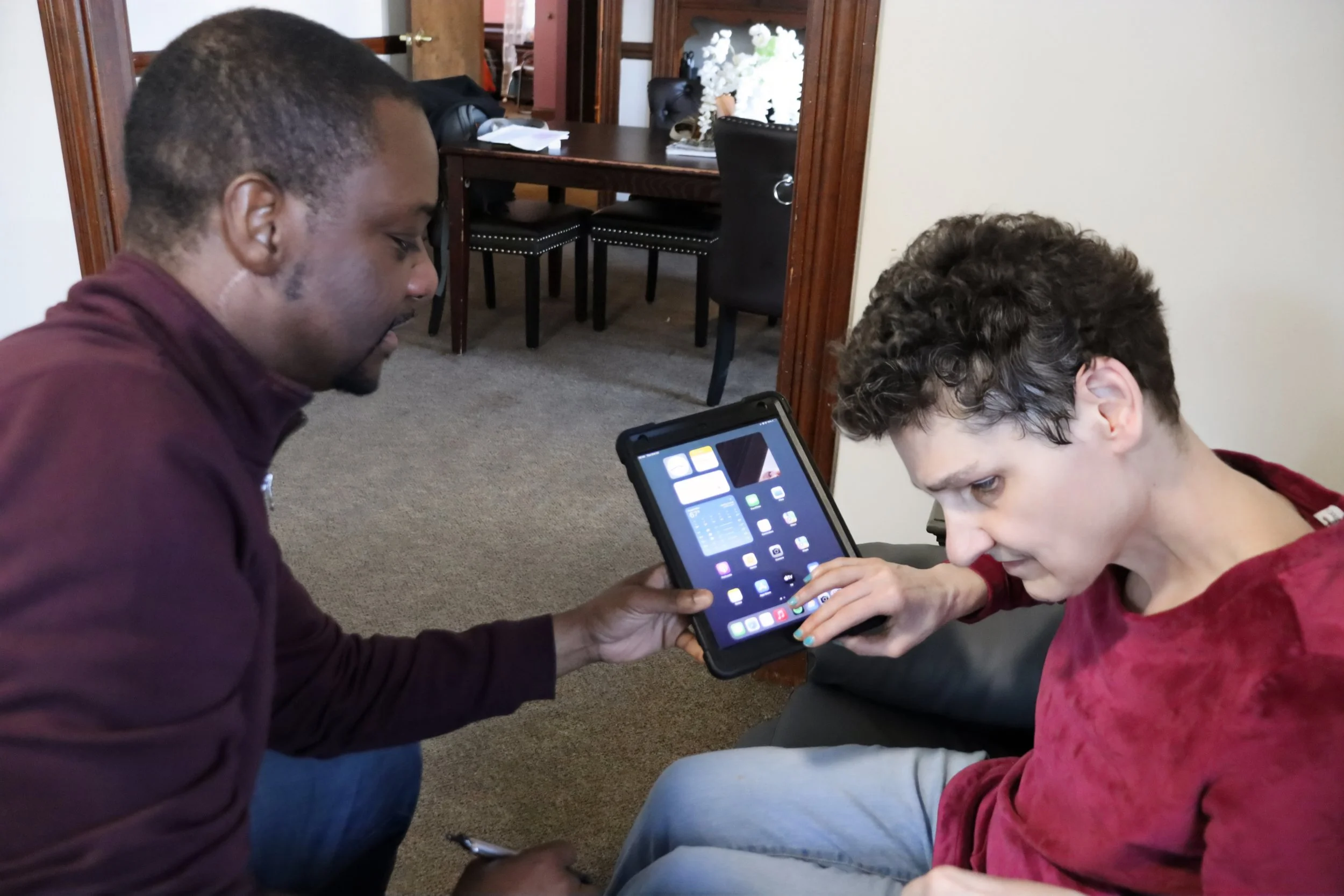 The author sits in a chair with her ipad, receiving training from a TechConnect employee