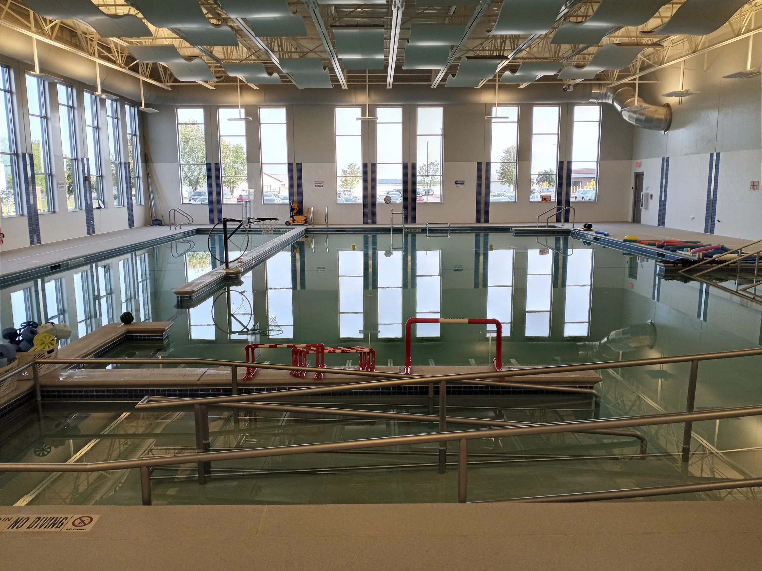 An indoor pool with still water as smooth as glass is surrounded by therapy equipment