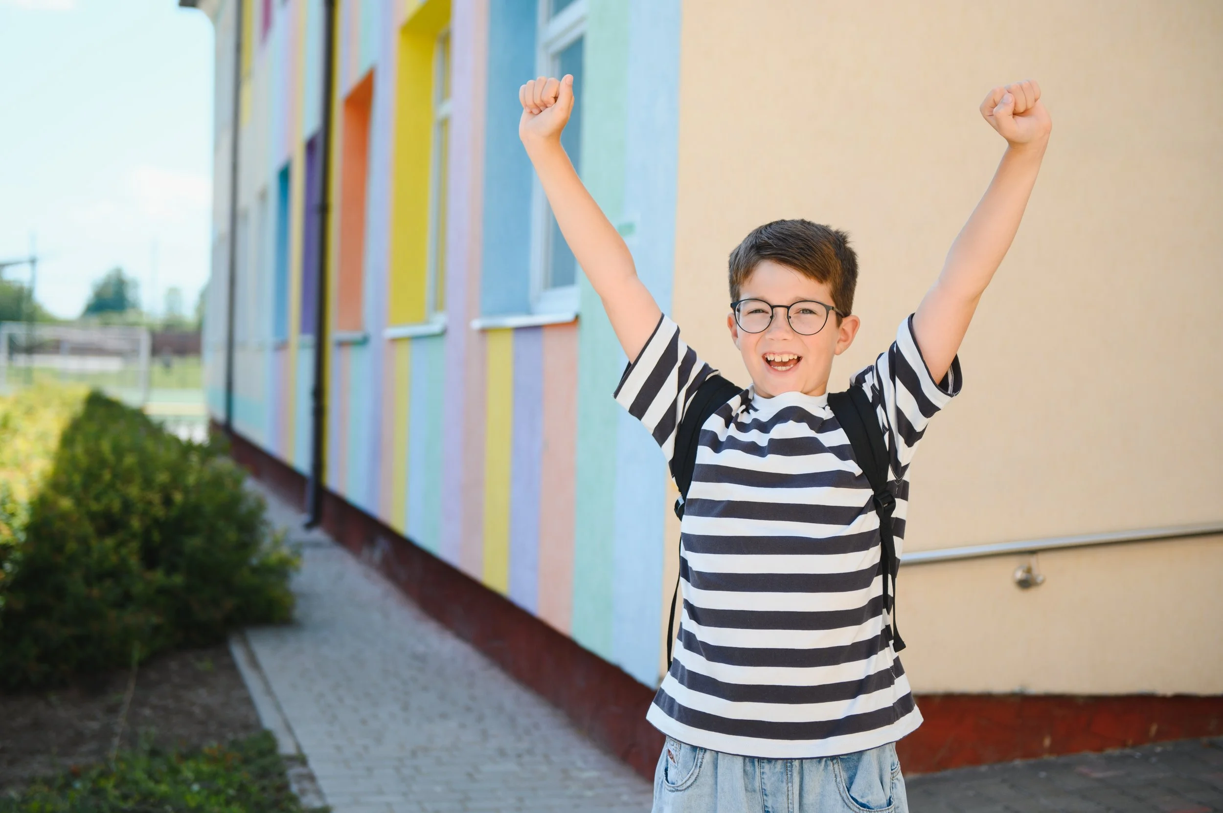 Enthusiastic student celebrating back to school outside colorful building