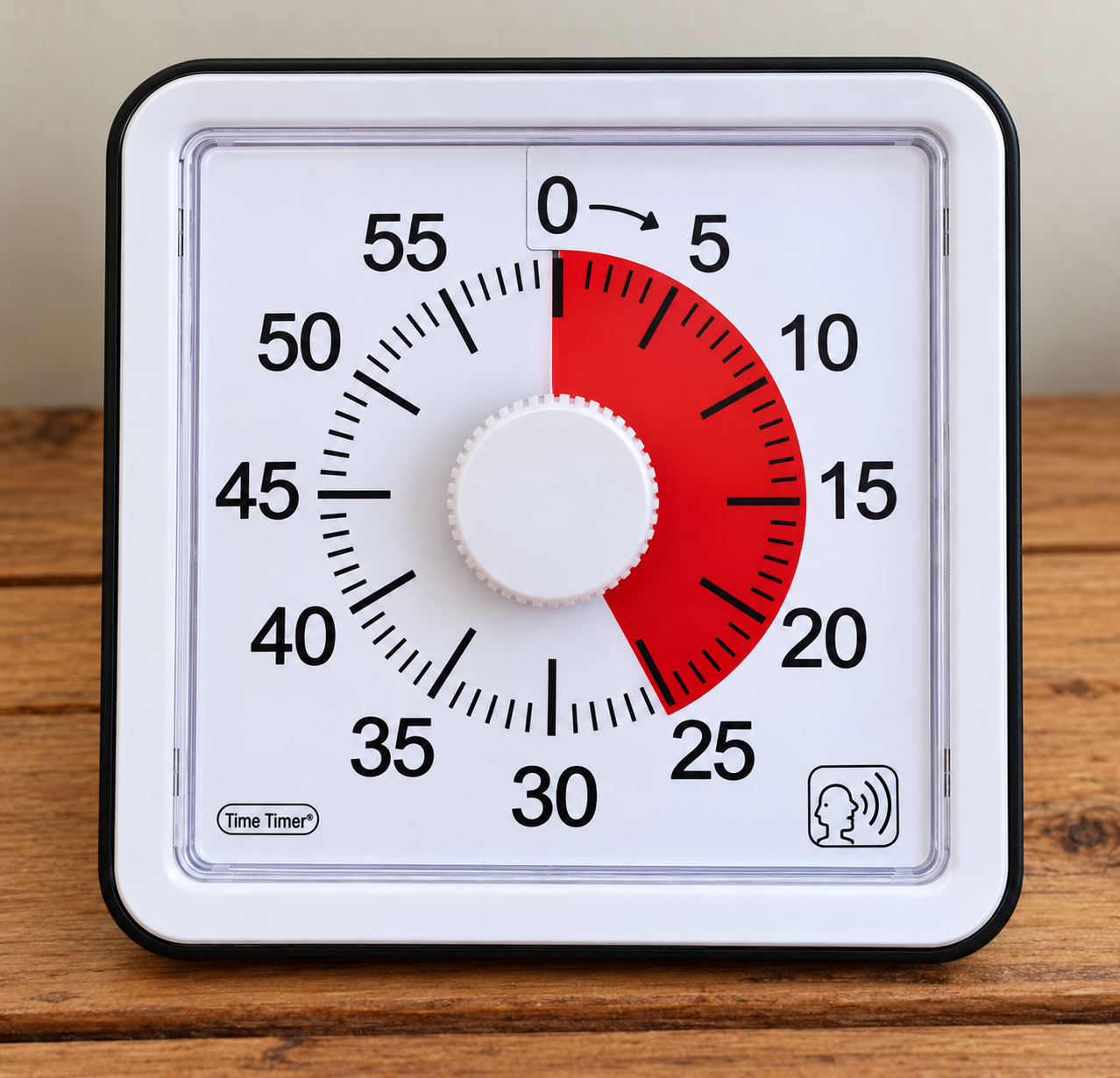 A square visual timer sits on a wooden surface, with a numbered dial from 0 to 55 minutes and a red shaded section indicating the remaining time.