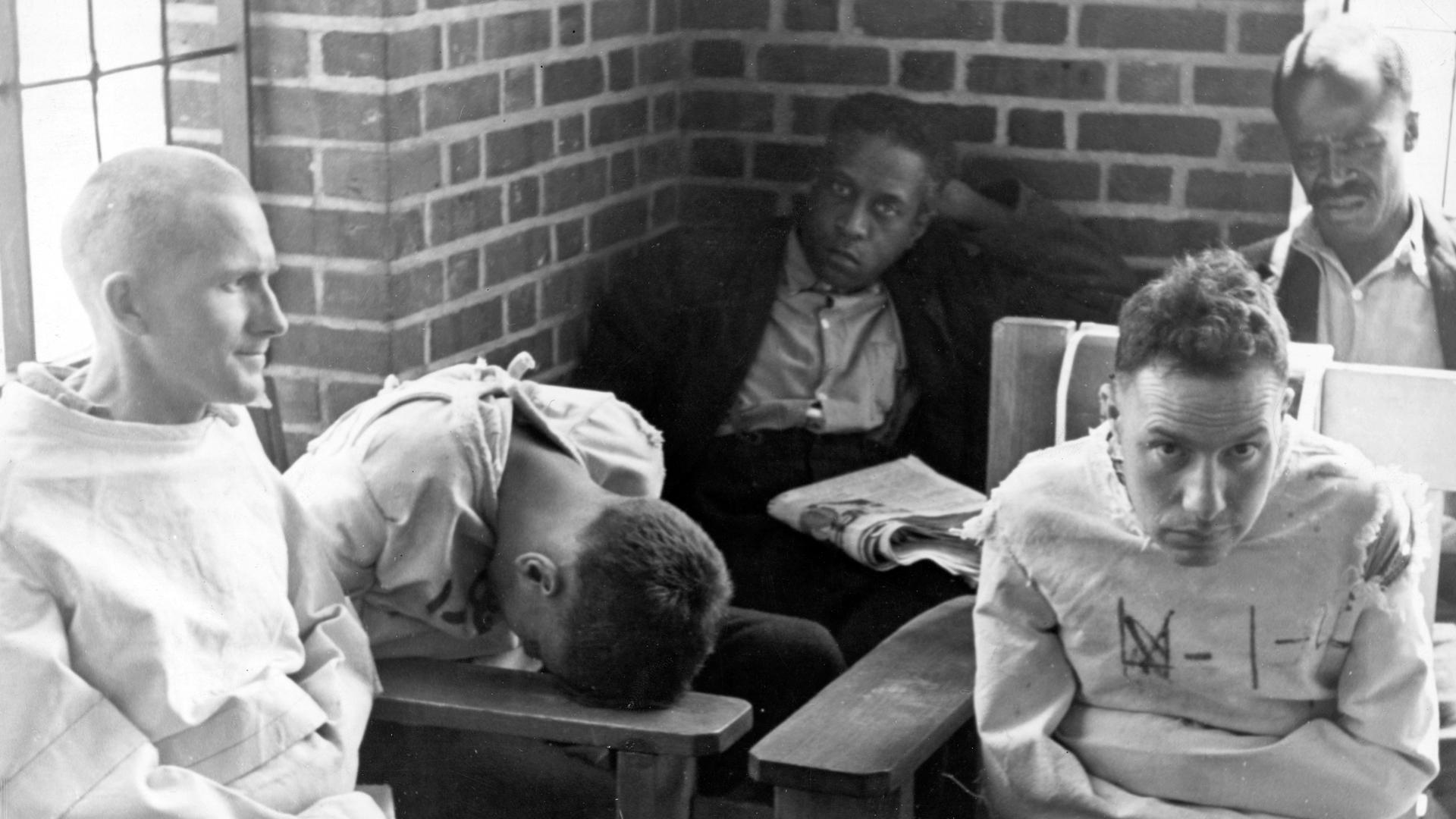 A vintage photo of men confined to straight jackets