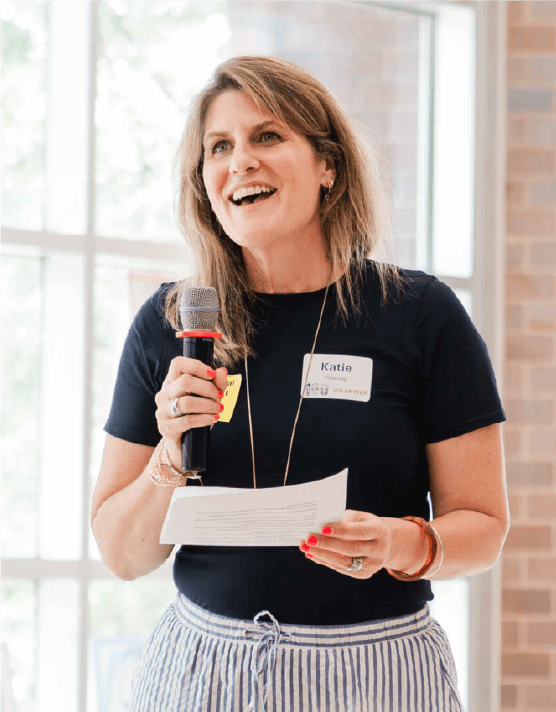 Katie Manning holds a microphone while giving a presentation about her art