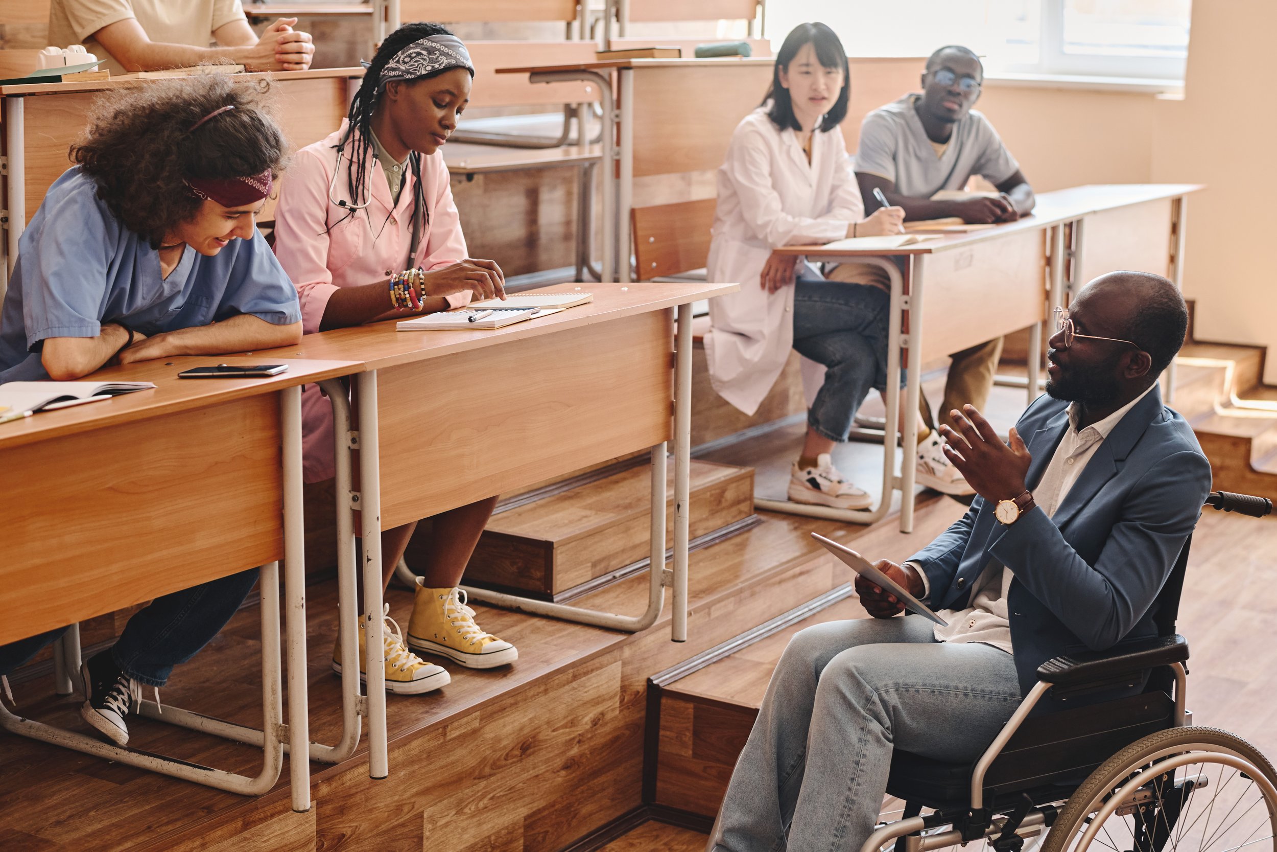 A man who is in a wheelchair speaks to a class of medical students