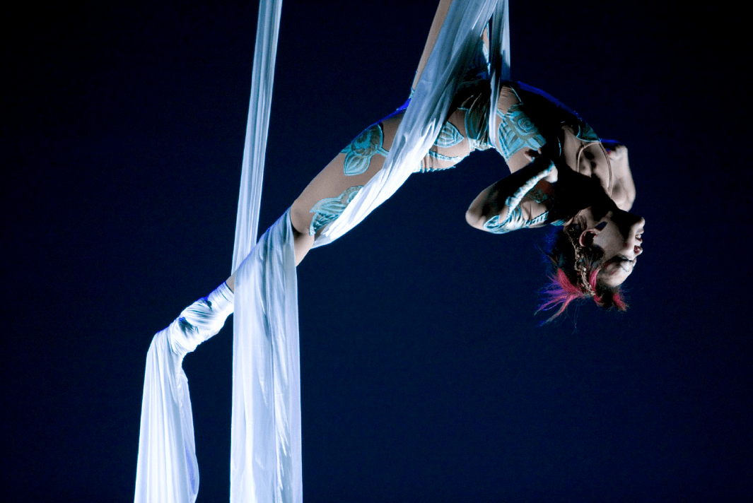 Sora Kasuga flies over the audience suspended by fabric tethers