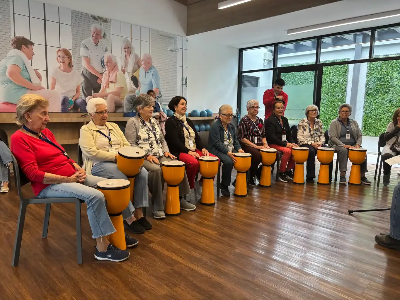 9 elderly women form a drum circle holding bongos.