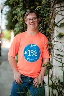 A portrait of Chris standing outside by an ivy-covered wall