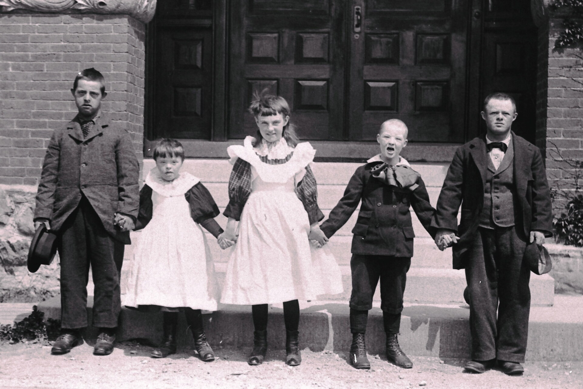 A vintage photo of five children with Down syndrome standing in a line, holding hands