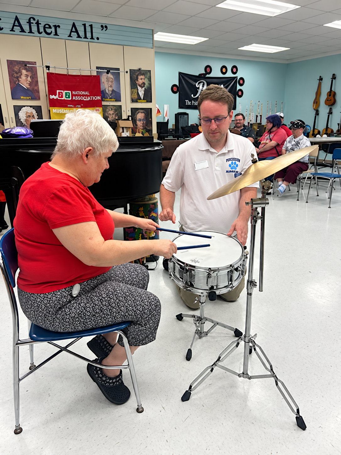 Jacob helps an older woman play the snare drum.