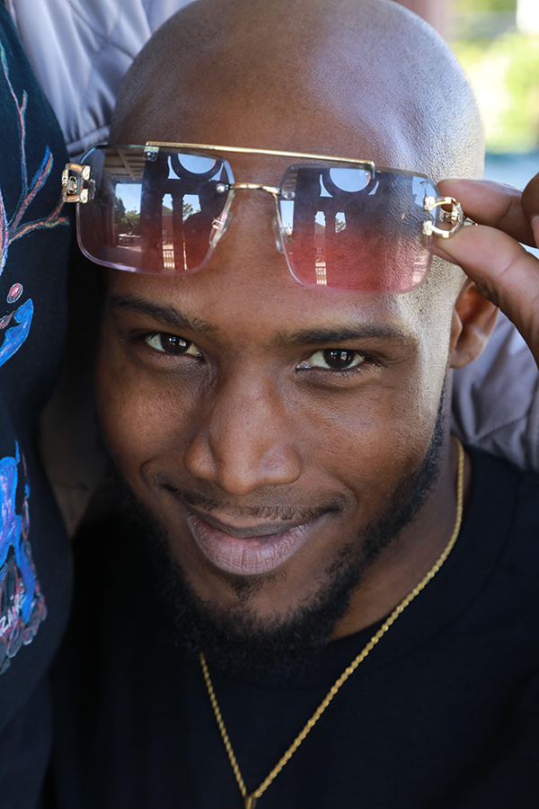 A portrait of Aaron, smiling slyly while lifting this sunglasses to his forehead.