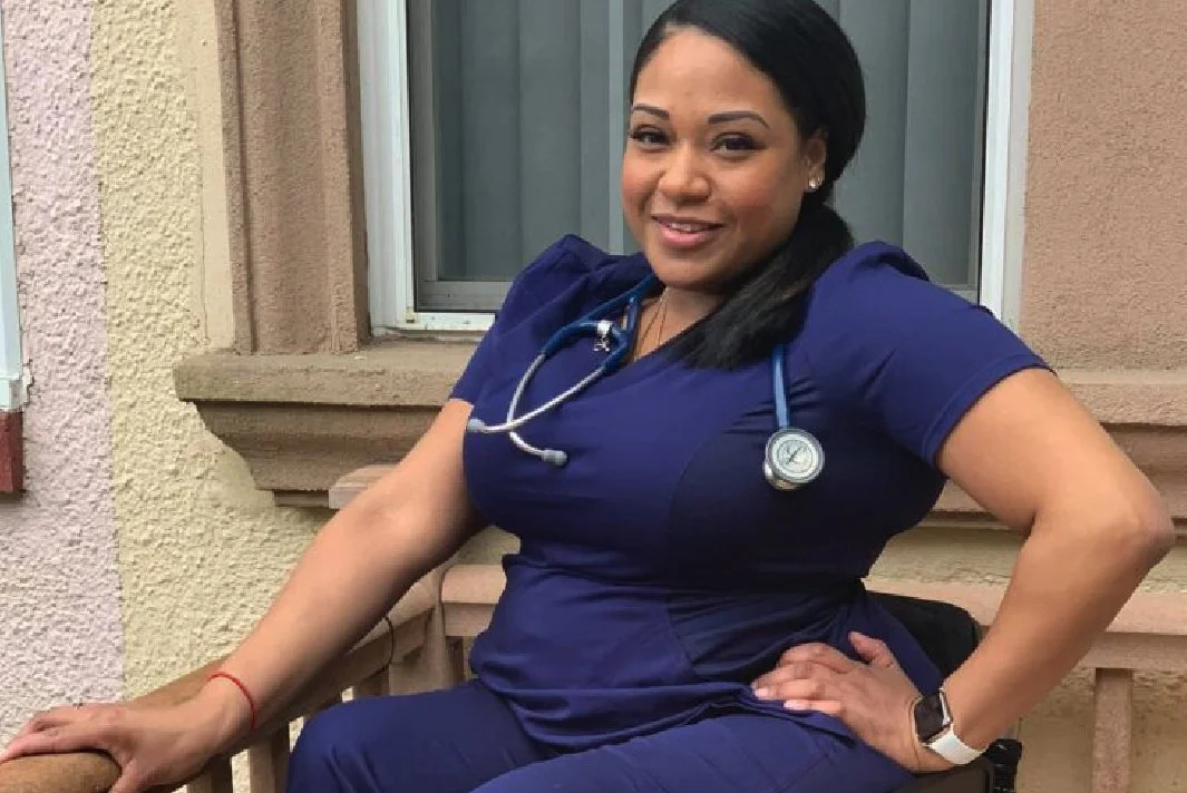 A photo of Andrea in her purple scrubs and stethoscope