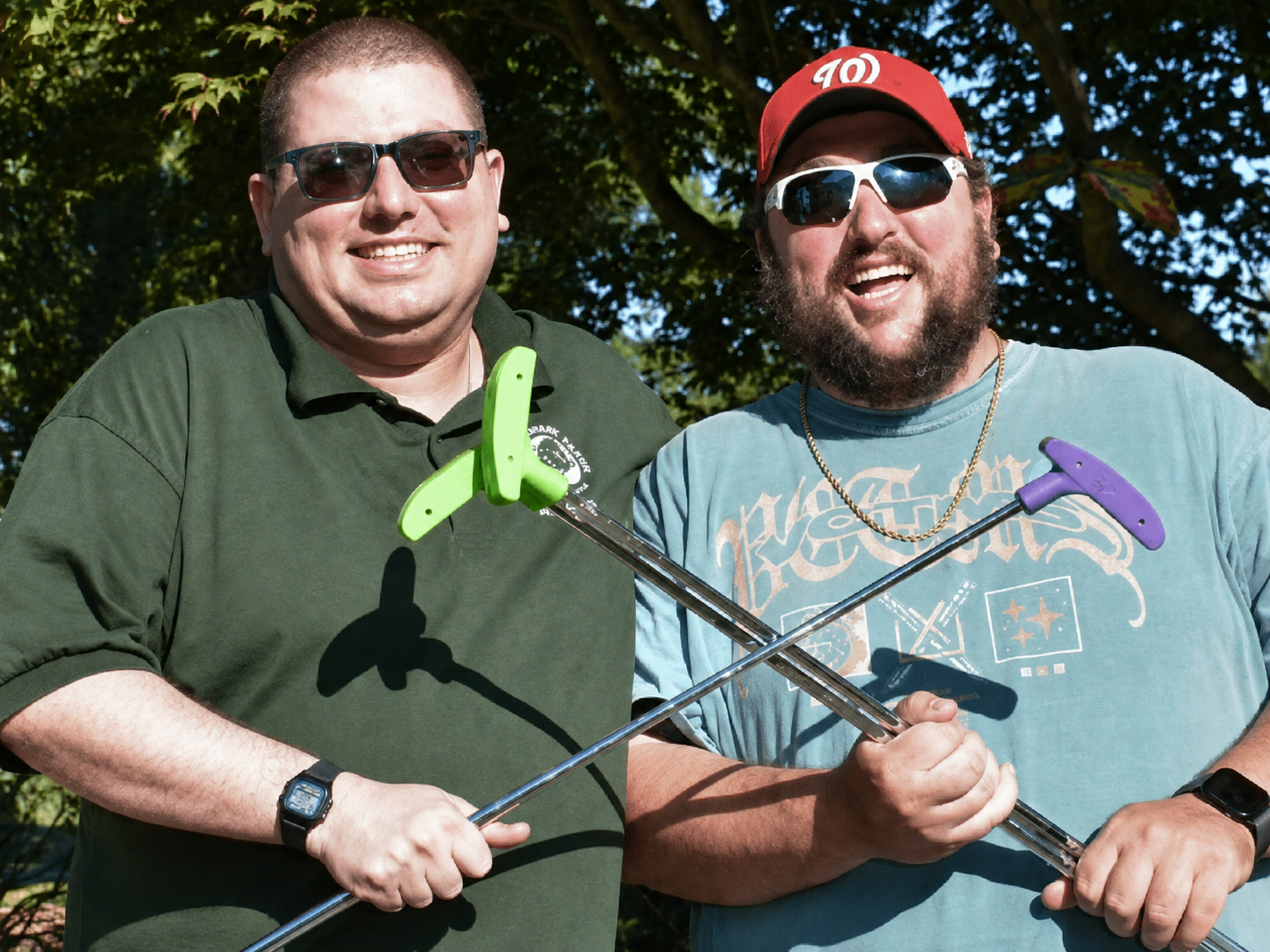 Two men laugh while holding putt-putt golf clubs