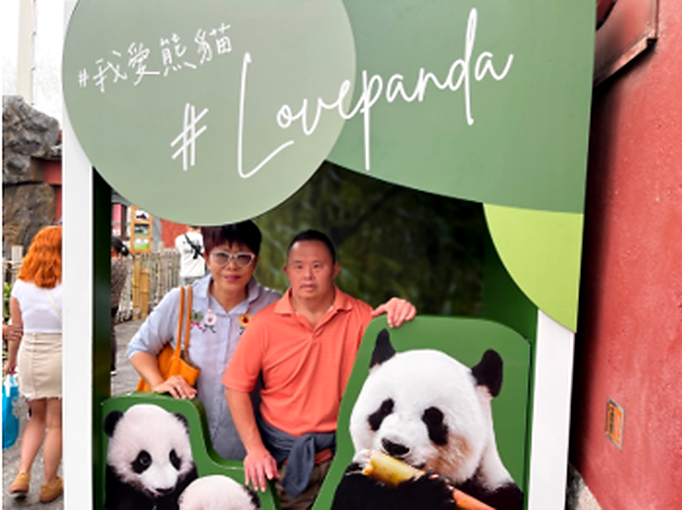 Koji and his mother pose at the zoo with a panda photo cutout
